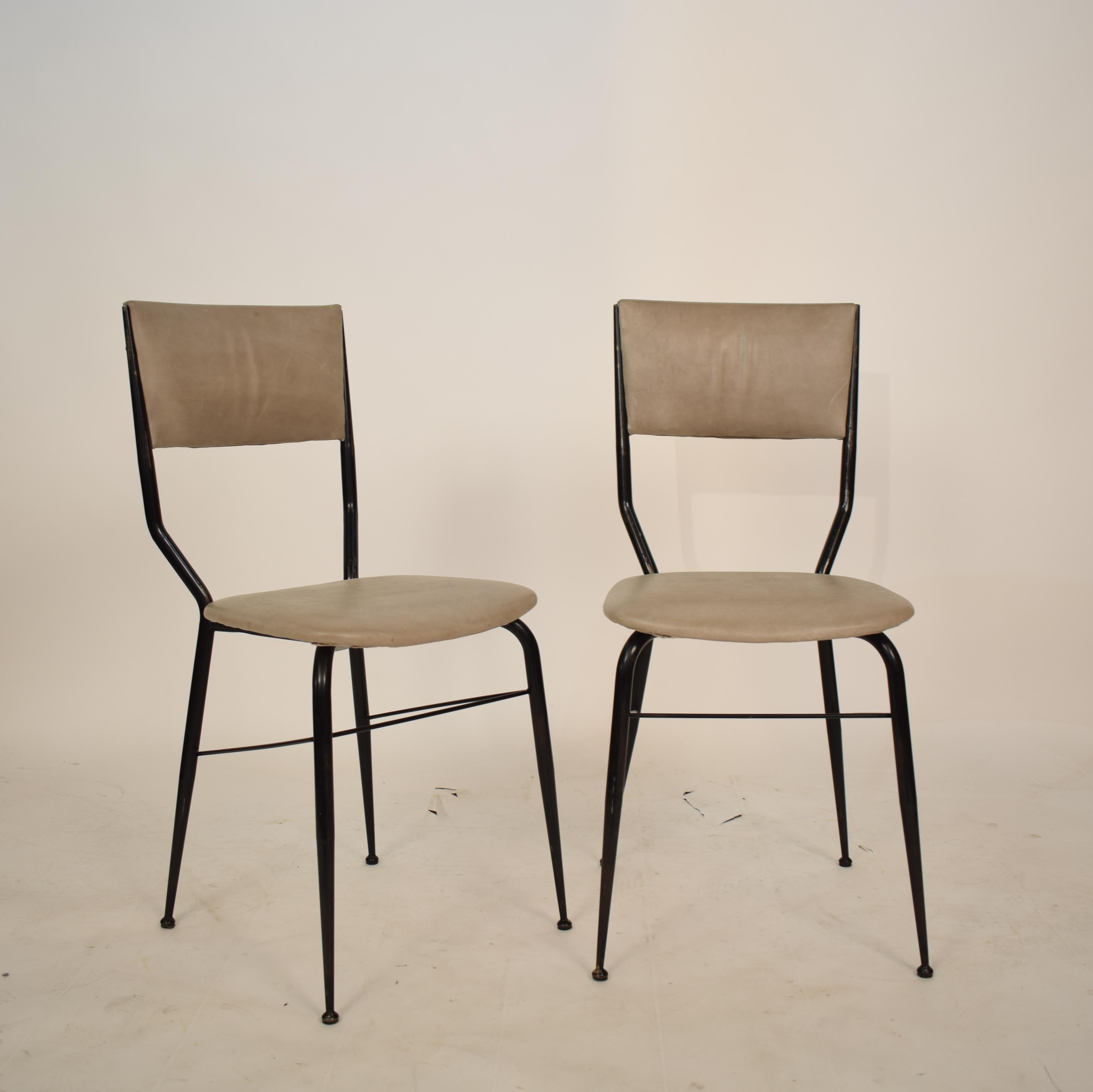 This pair of midcentury dining chairs from the 1950s where designed and manufactured in Italy. The chairs consist of an elegant black metal frame and a padded grey leather seat and backrest. The chairs has been newly reupholstered in gray leather.