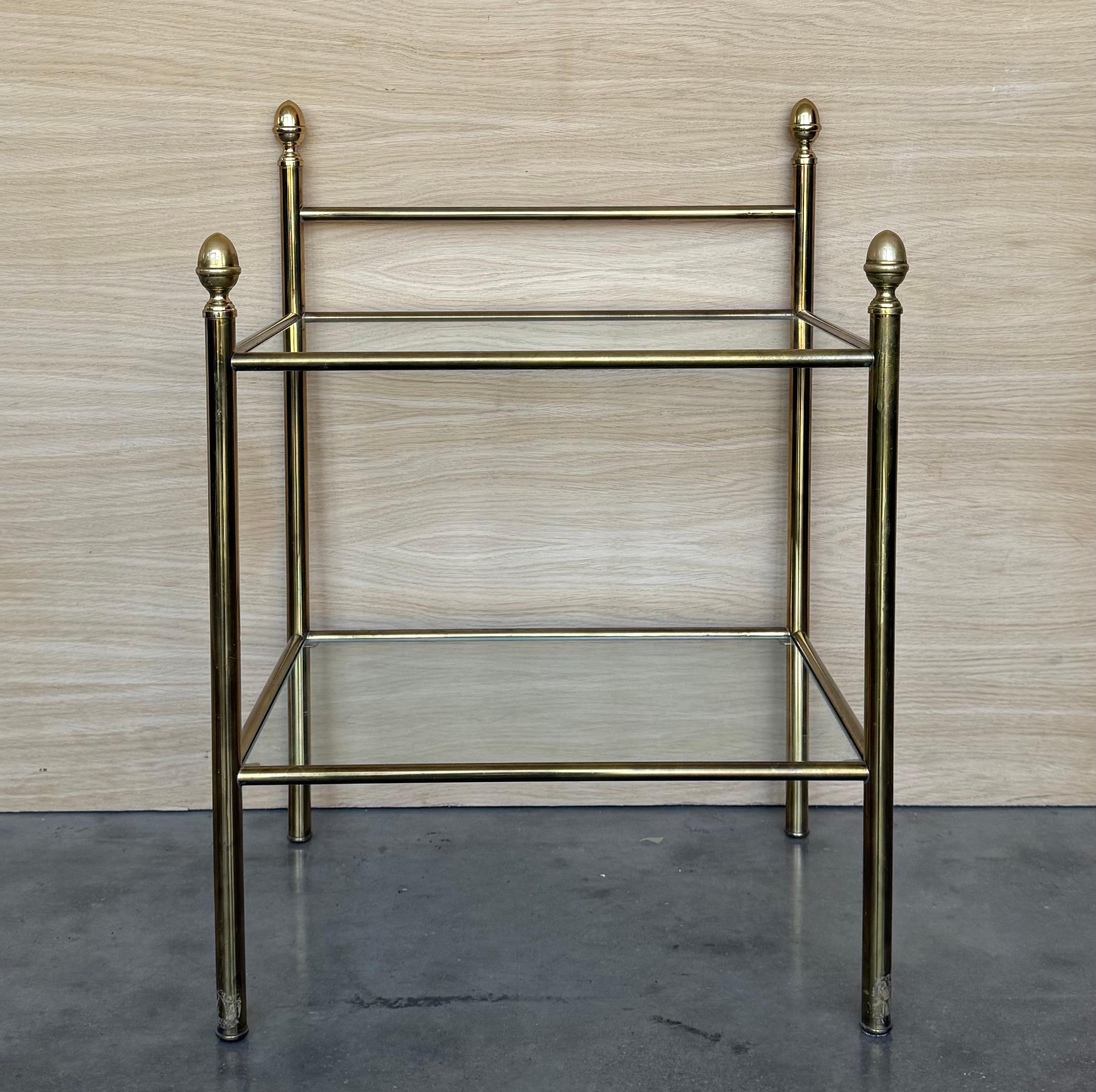 Pair of midcentury Italian two tier brass and glass nightstands with crest.
Simple tables with a low grid shelve and glass top. 

Height to the glass top : 51.50in
