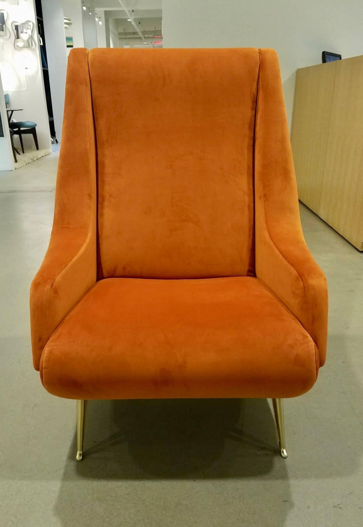 A pair of midcentury Italian newly upholstered burnt orange ultra suede armchairs attributed to ISA with generously proportioned, slanted high backs, and sinuous shaped arms around tightly upholstered seats, resting on gold-toned, splayed and