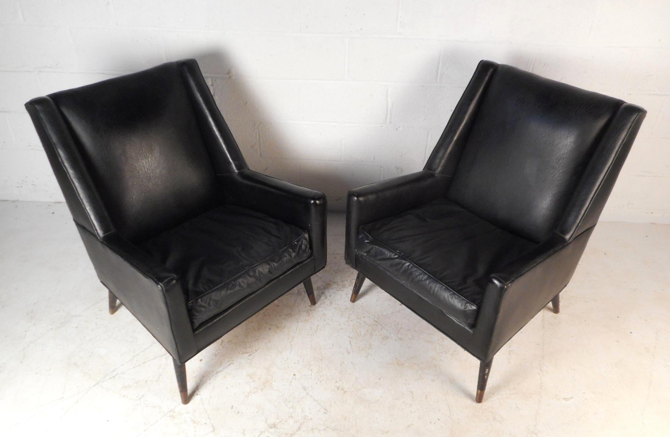 This pair of Italian lounge chairs are sure to add style to any seating arrangement. The chairs are covered in a soft dark vinyl upholstery with padded back rests and removable cushions for comfortable lounging. Beneath the chairs are splayed and