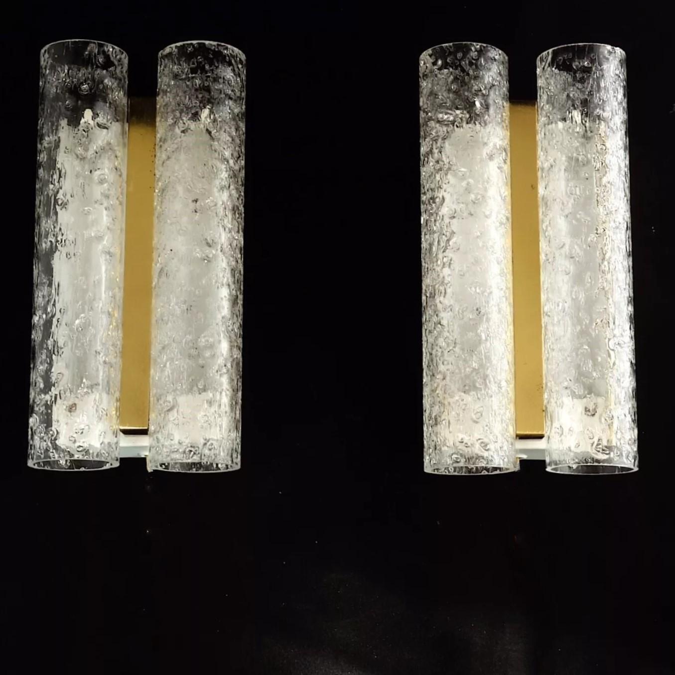 Preciosa pareja de apliques de pared de dos luces de cristal de Murano fabricados en Italia en la década de 1970, de elegante diseño modernista con doble cilindro de cristal helado de Murano, montados en latón y metal. Cada aplique admite dos bases