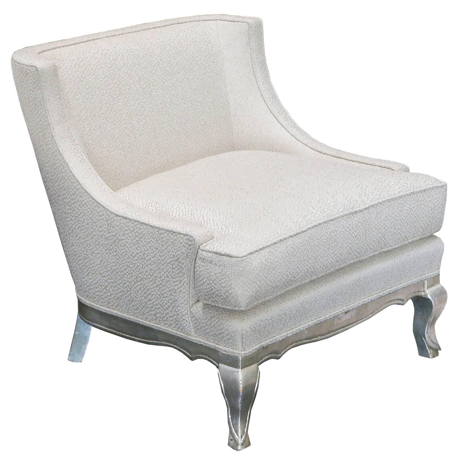 Elegant pair of lounge chairs with carved legs and base in distressed silver leaf. Curved arms with tight back and seat cushion are upholstered in ivory linen and silk fabric.