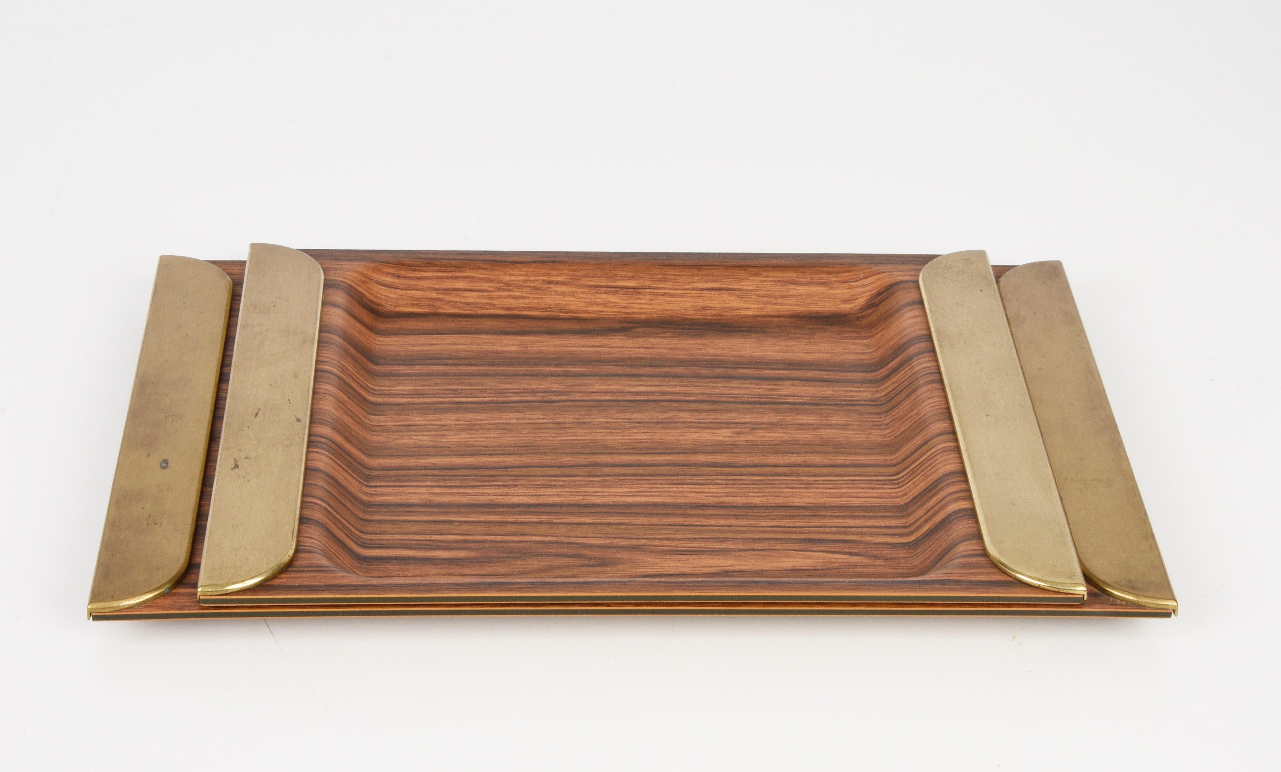 Amazing pair of midcentury trays in plastic laminate with solid brass handles. These fantastic pieces were designed in Italy during the 1970s.

This set is wonderful as the plastic laminate simulate wood perfectly but is lighter and simpler to