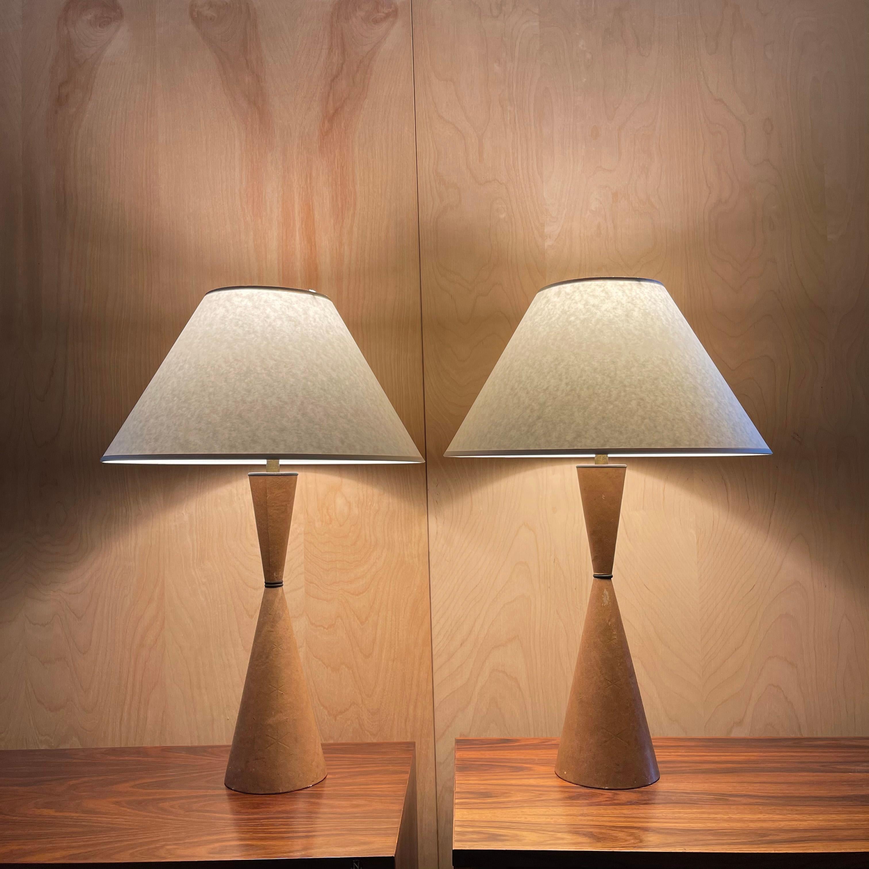 Pair of handsome, Mid-Century Modern, table lamps feature embossed leather, hourglass shaped bases with brass necks and tapered, coolie paper shades that measure 18 diameter x 10 ht inches.
