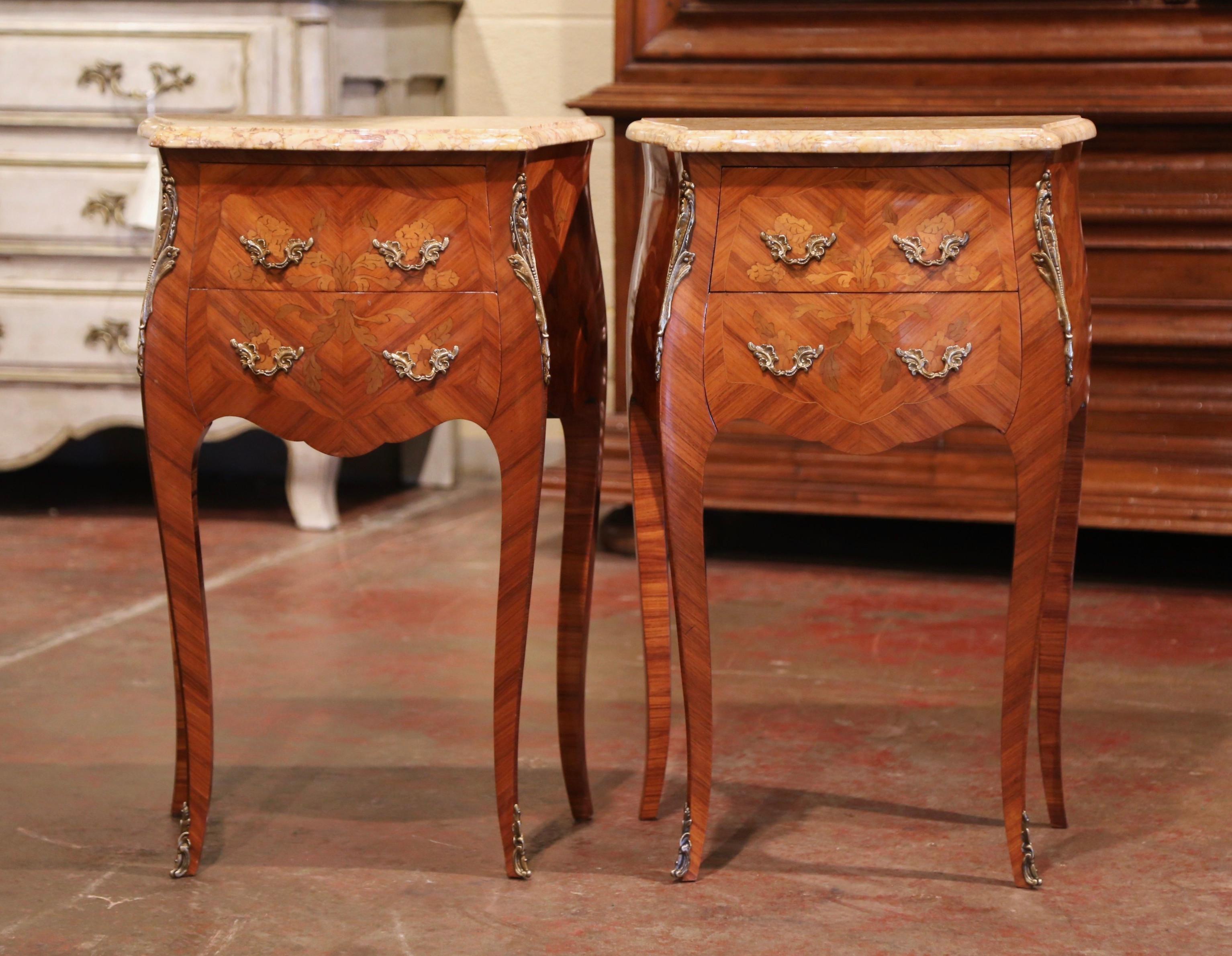 These elegant bedside tables were created in France, circa 1950. Bombe in shape on all three sides, the fruitwood cabinets stand on cabriole legs ending with decorative brass sabot feet; both sides with serpentine shape have inlaid veneer chevron