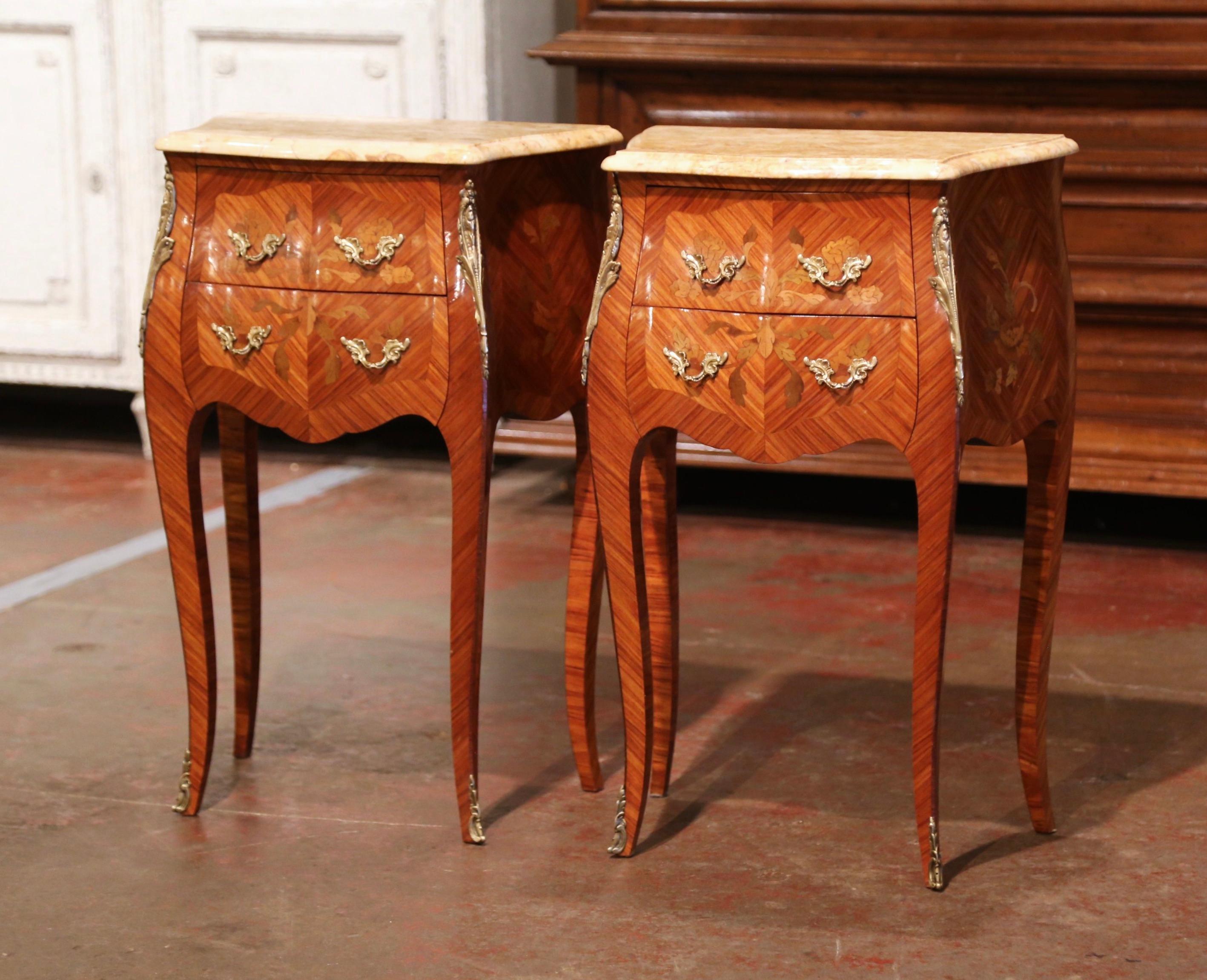 These elegant bedside tables were created in France, circa 1960. Bombe in shape on all three sides, each fruitwood cabinet stands on cabriole legs ending with front brass sabot feet; both sides with serpentine shape have inlaid veneer chevron