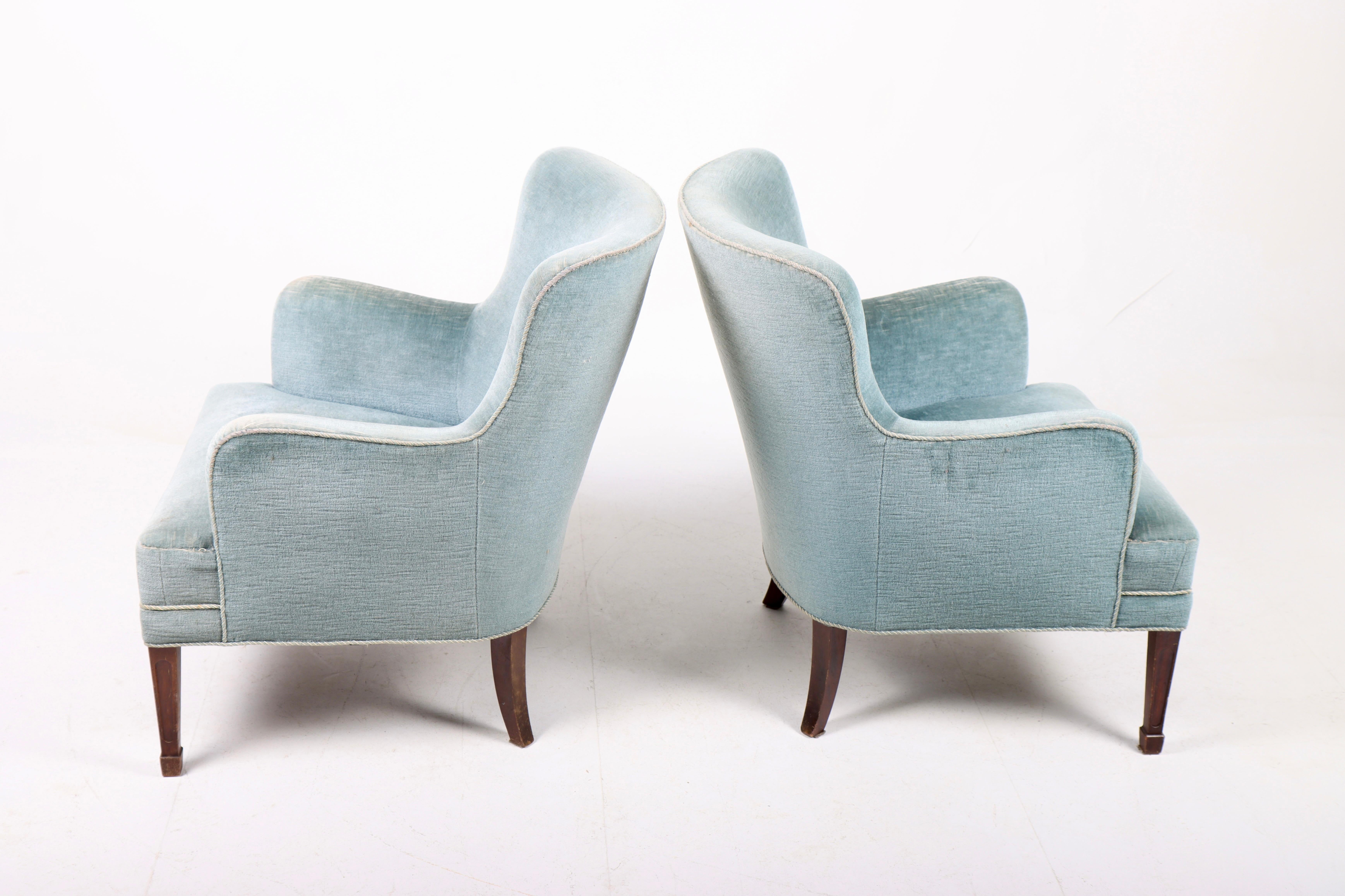Pair of Classic midcentury lounge chairs upholstered in fabric standing on solid mahogany legs. Designed by Danish architect Frits Henningsen, circa 1940. Made in Denmark. Great original condition.