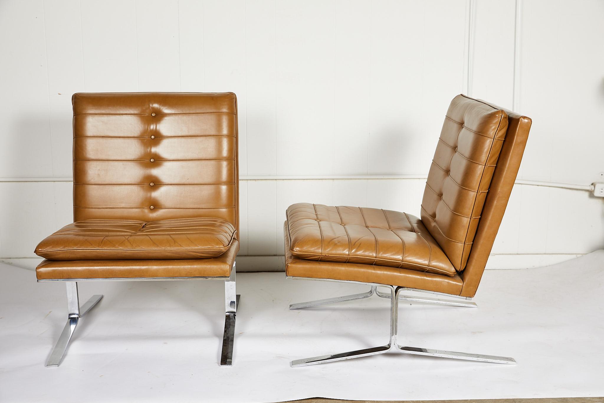 Stylish pair of American midcentury armless lounge chairs with channeled camel leather seats and backs, on bright chrome cantilevered bases. The design is influenced by the iconic Barcelona chair designed by Mies van der Rohe. The chairs were