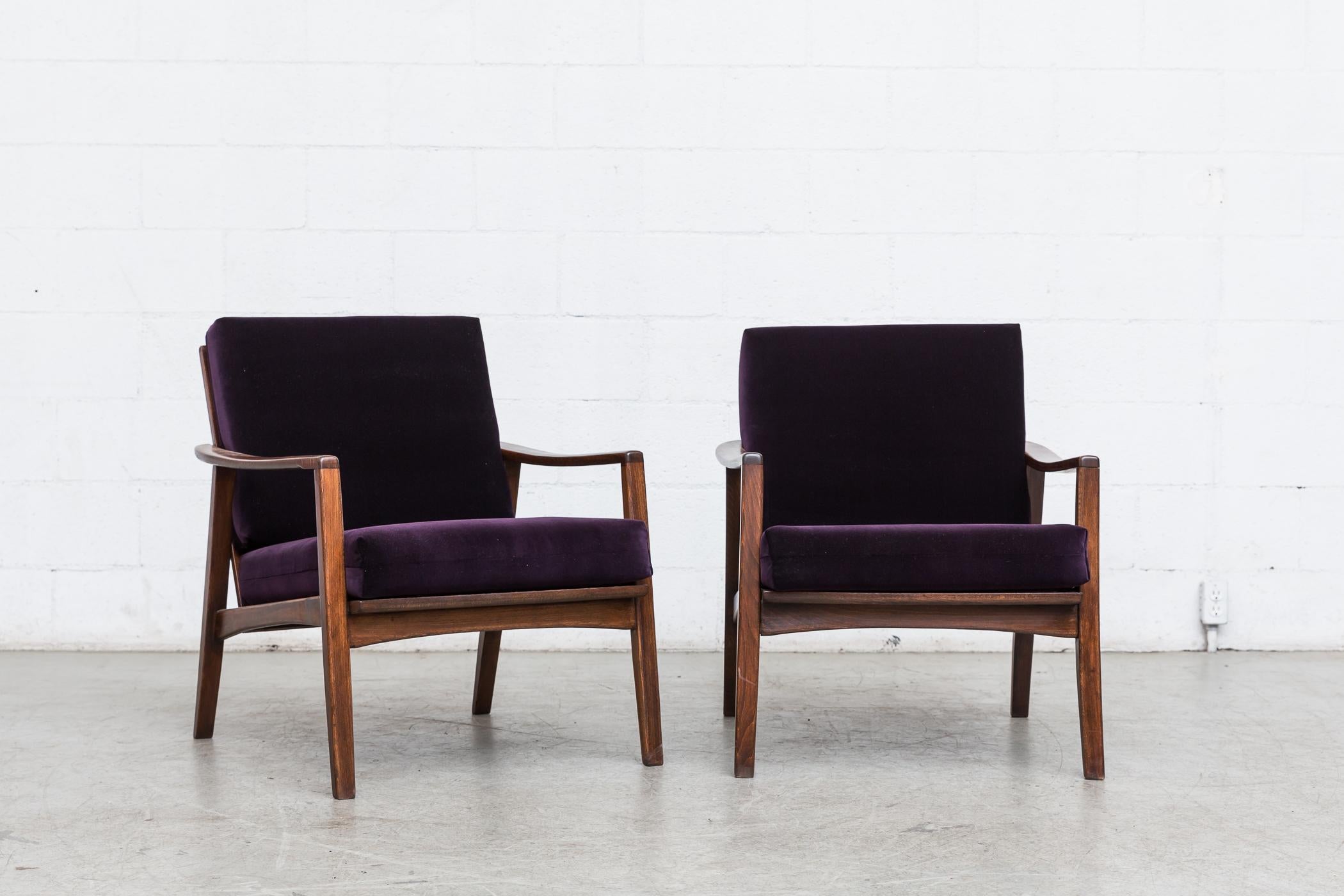 Pair of midcentury lounge chairs with rich dark wood frames and bow tie shaped back slat supports. Newly upholstered amethyst velvet cushions. Frames in original condition. Set price.