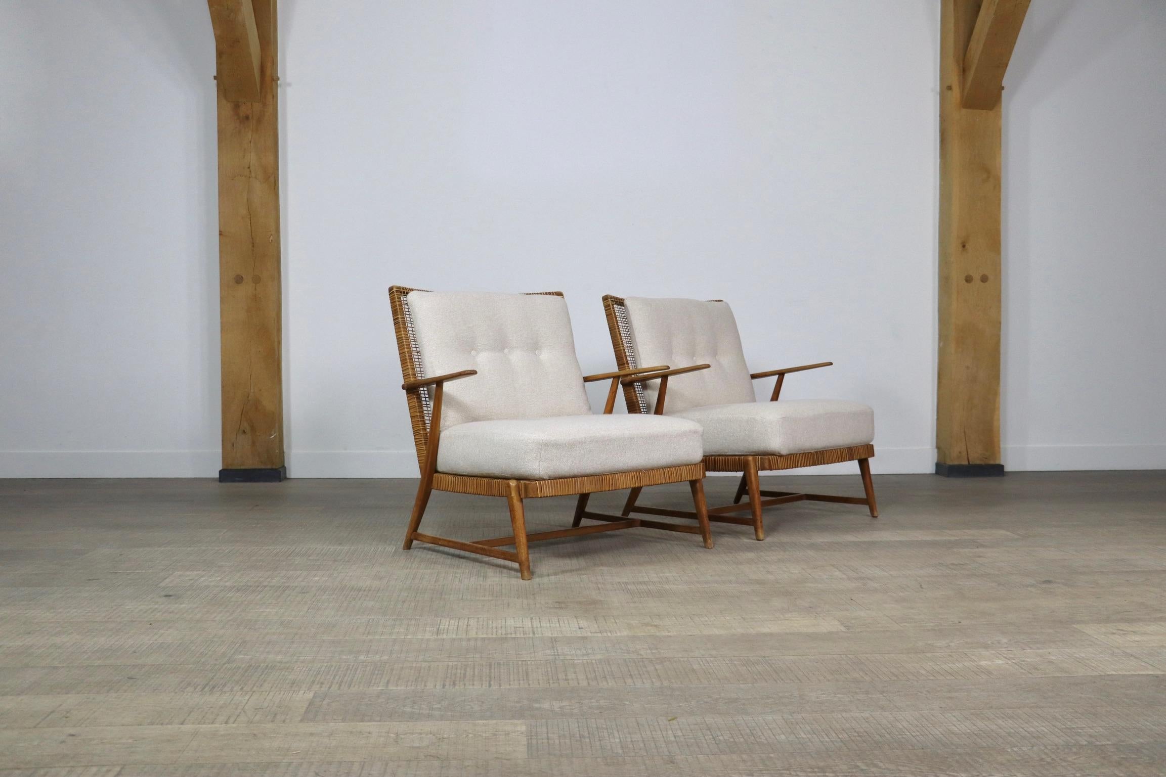 Pair of Midcentury lounge chairs in solid oak wooden frame with woven cane seating and backrest and newly upholstered cushions in a thick, high quality textured cream fabric, Germany 1950s. 

A sophisticated design with minimalist lines and a very