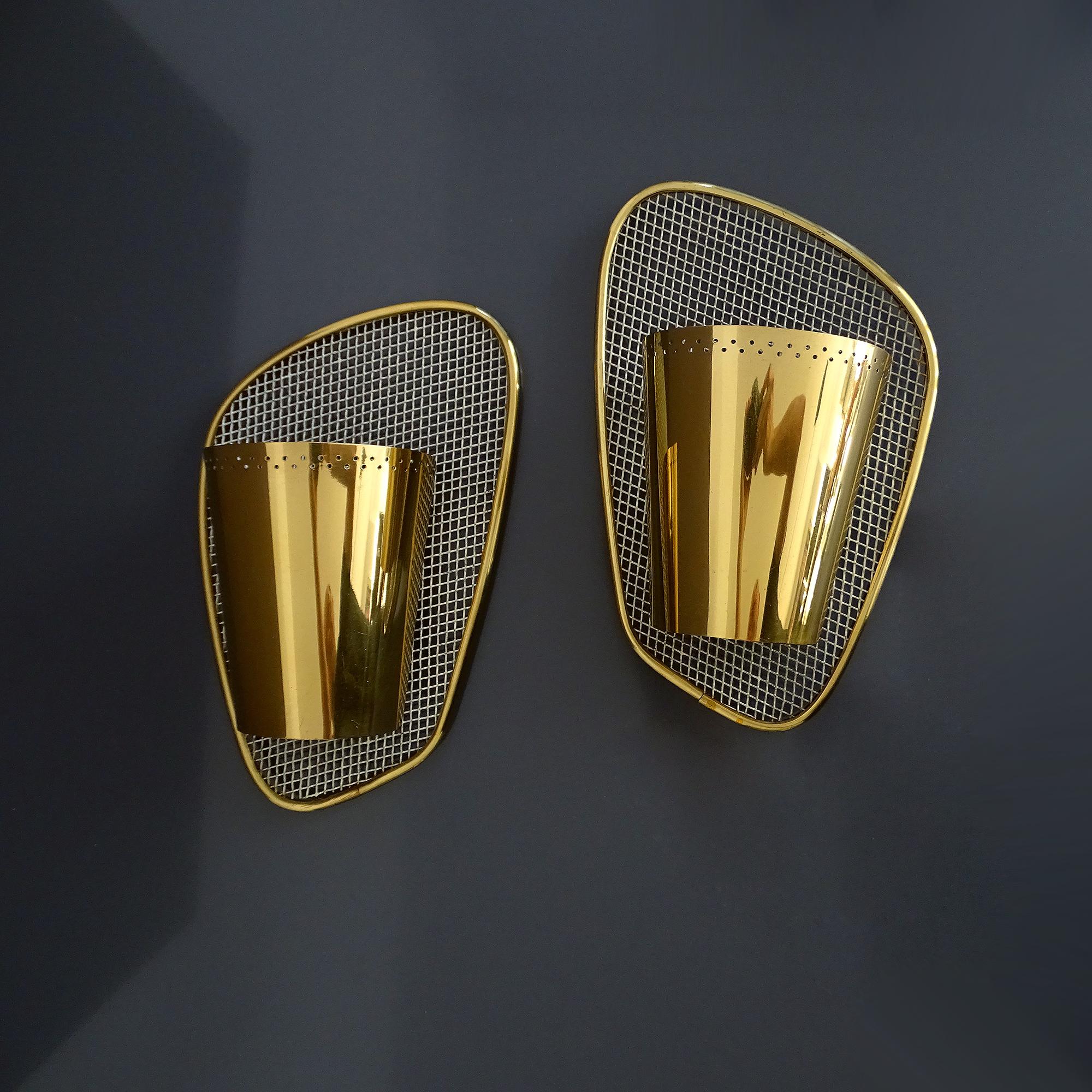 Pair of very stylish midcentury  sconces, featuring a louvered arched brass shade mounted on an white enameled asymmetric grid with brass frame
Measures: H 11.82 in. x W 7.49 in. x D 3.94 in.
H 30 cm x W 19 cm x D 10 cm
One standard bulb each, 60