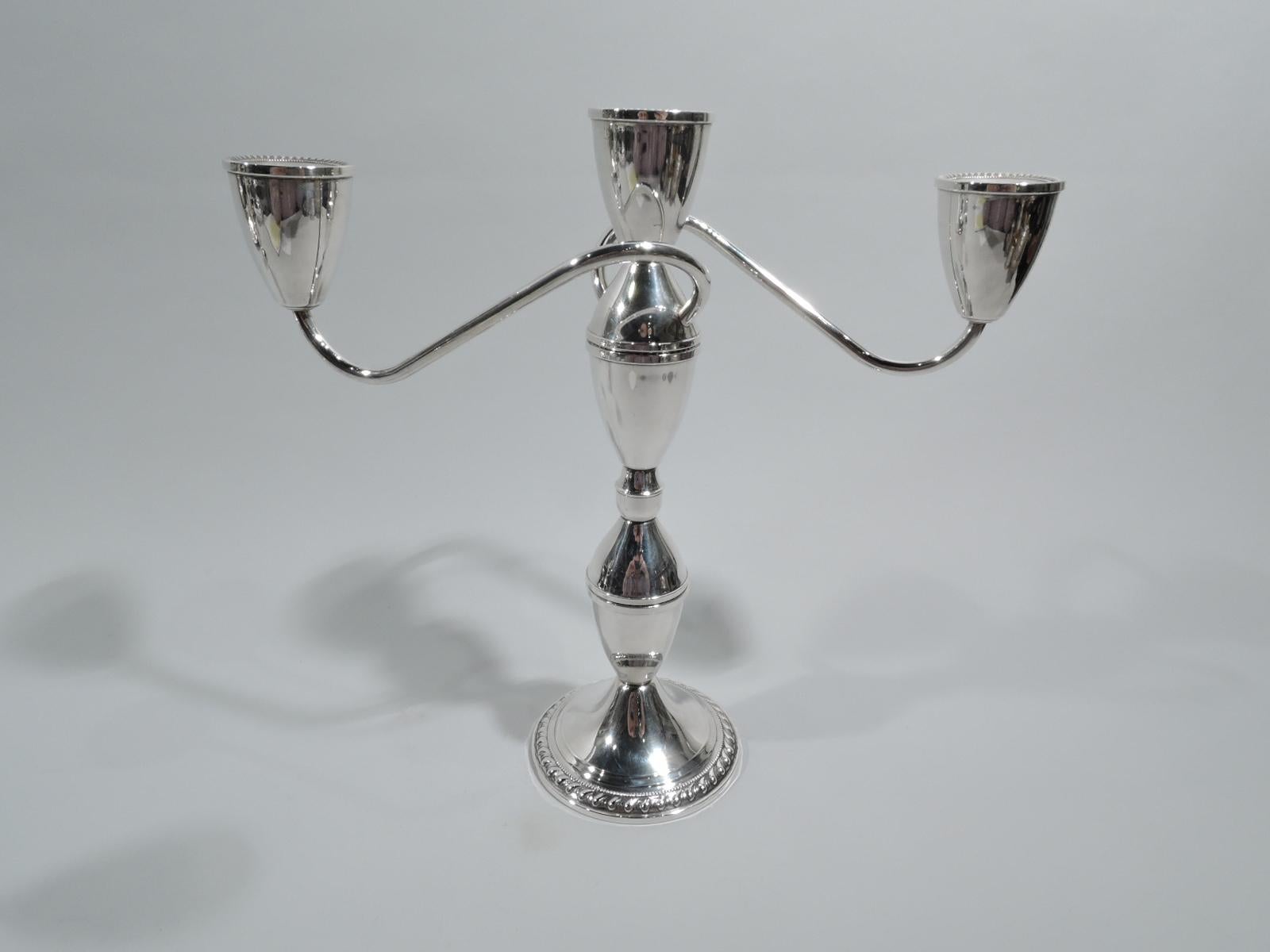 Pair of Midcentury Modern sterling silver 3-light candelabra. Each: Shaft comprising two pairs of cones surmounted by conical socket. Two scrolled arms, each terminating in single same socket. Raised and round foot. Gadrooning and beading. Converts