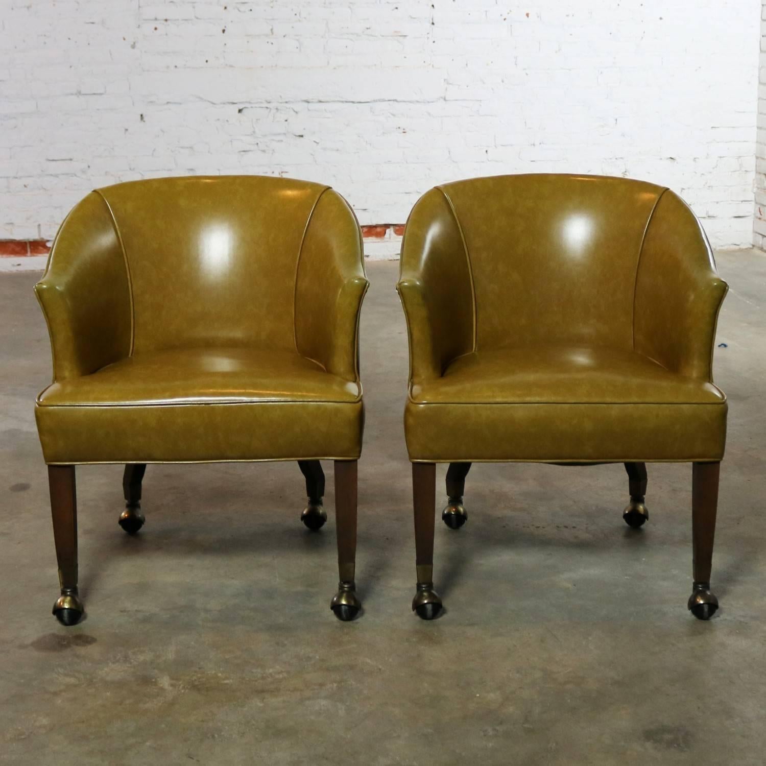 Handsome pair of midcentury rolling barrel shaped game chairs with olive or moss green vinyl Naugahyde and nail head accent. They are in wonderful vintage condition with normal age appropriate wear and tear apart from two small nicks in the vinyl