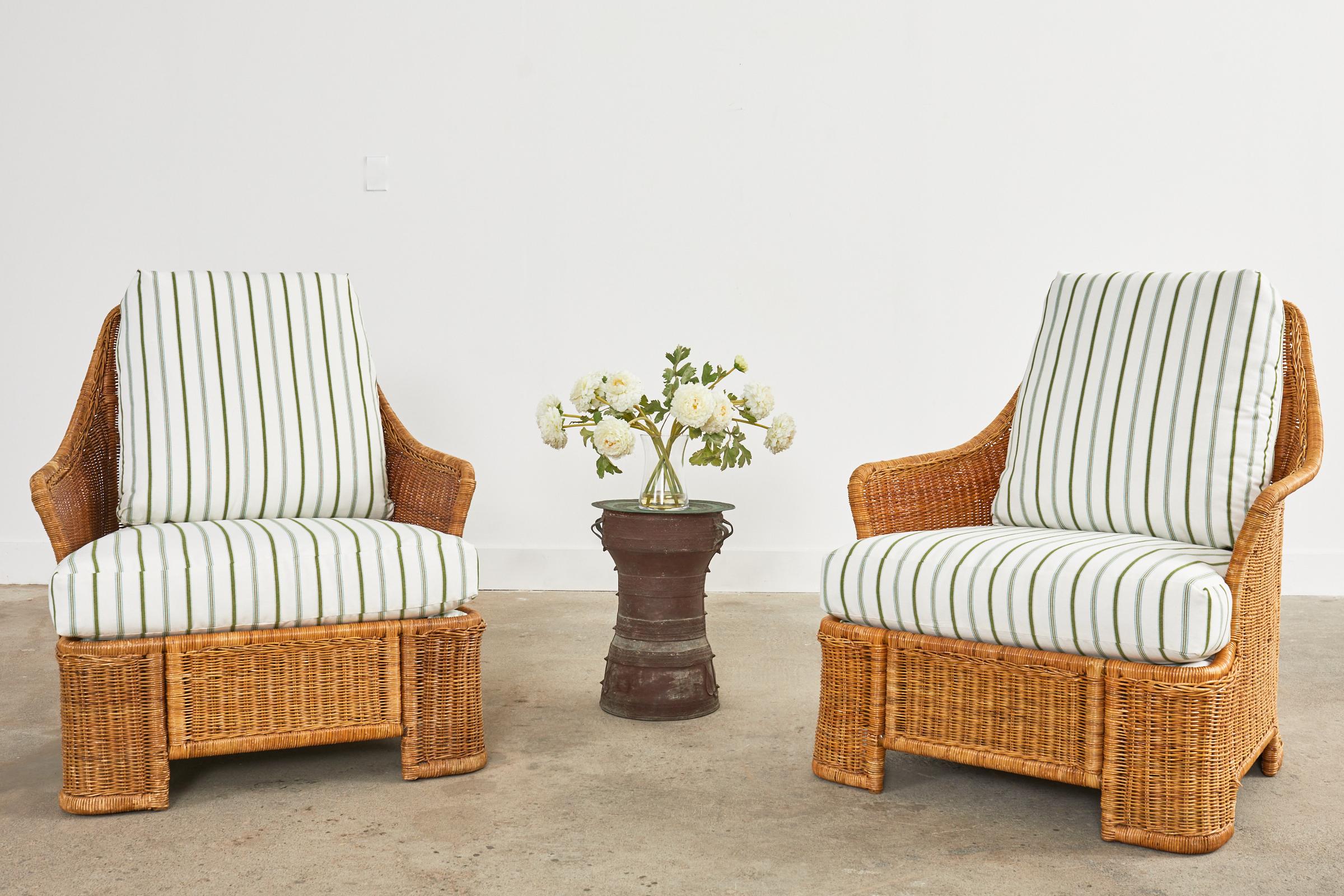 Sinuous pair of Mid-Century Modern wicker lounge chairs with newly upholstered seat cushions. The chairs feature a tubular metal frame which is very strong and stable wrapped with organic modern wicker. The frames have gracefully curved backs and