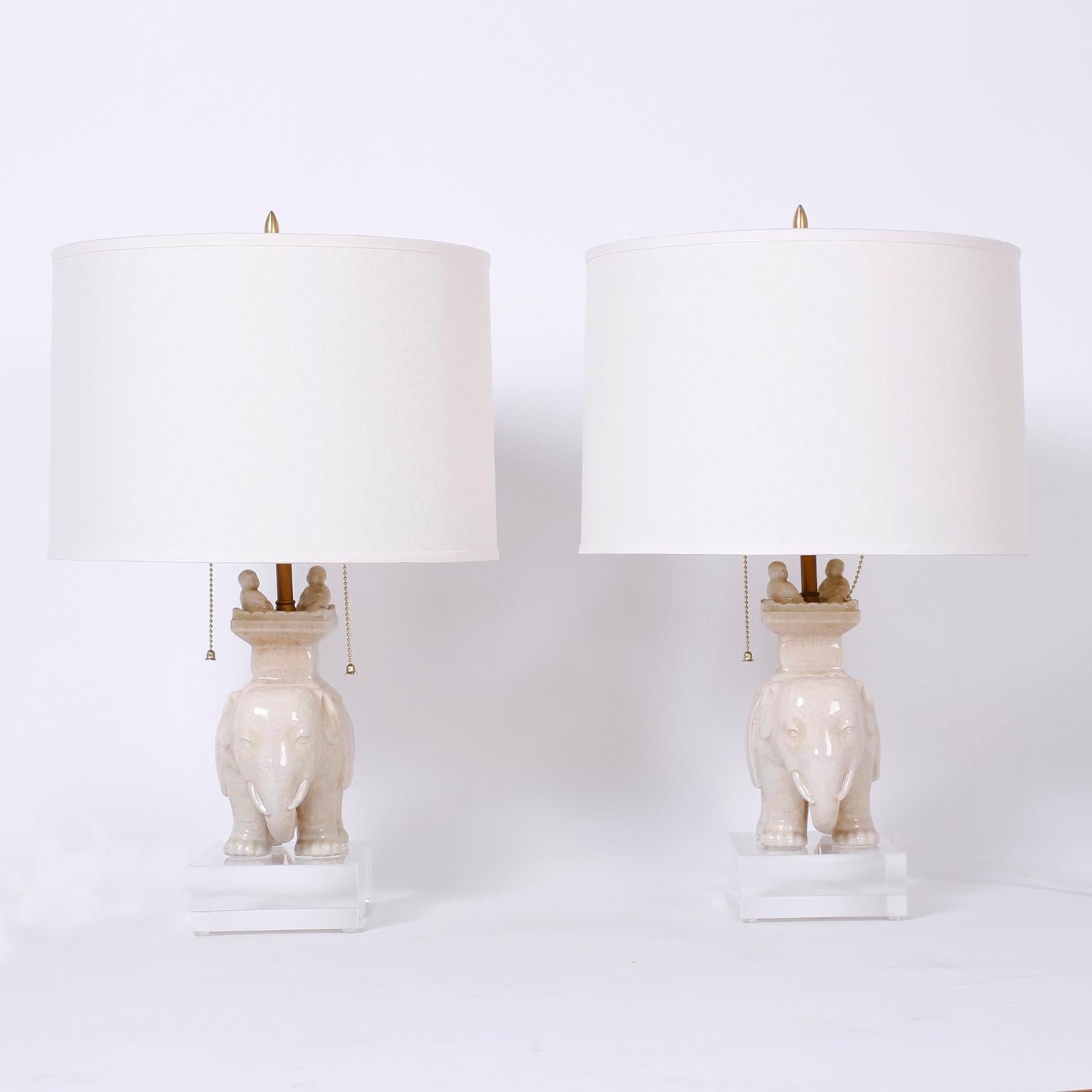 Intriguing pair of midcentury porcelain elephant table lamps with a cream color celadon crackle glaze and presented on thick Lucite bases.