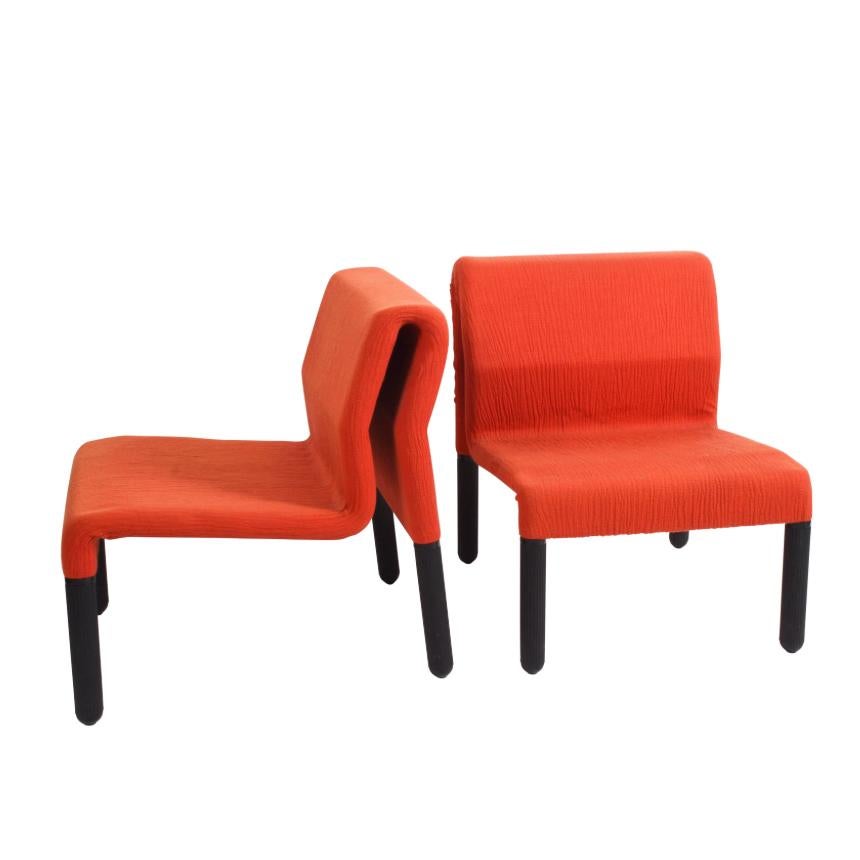 Pair of wonderful midcentury red fabric and black plastic armchairs. These amazing pieces were produced in Italy during the 1980s.

These items are extremely elegant and wonderfully innovative thanks to the two-angles back design.

This pair of