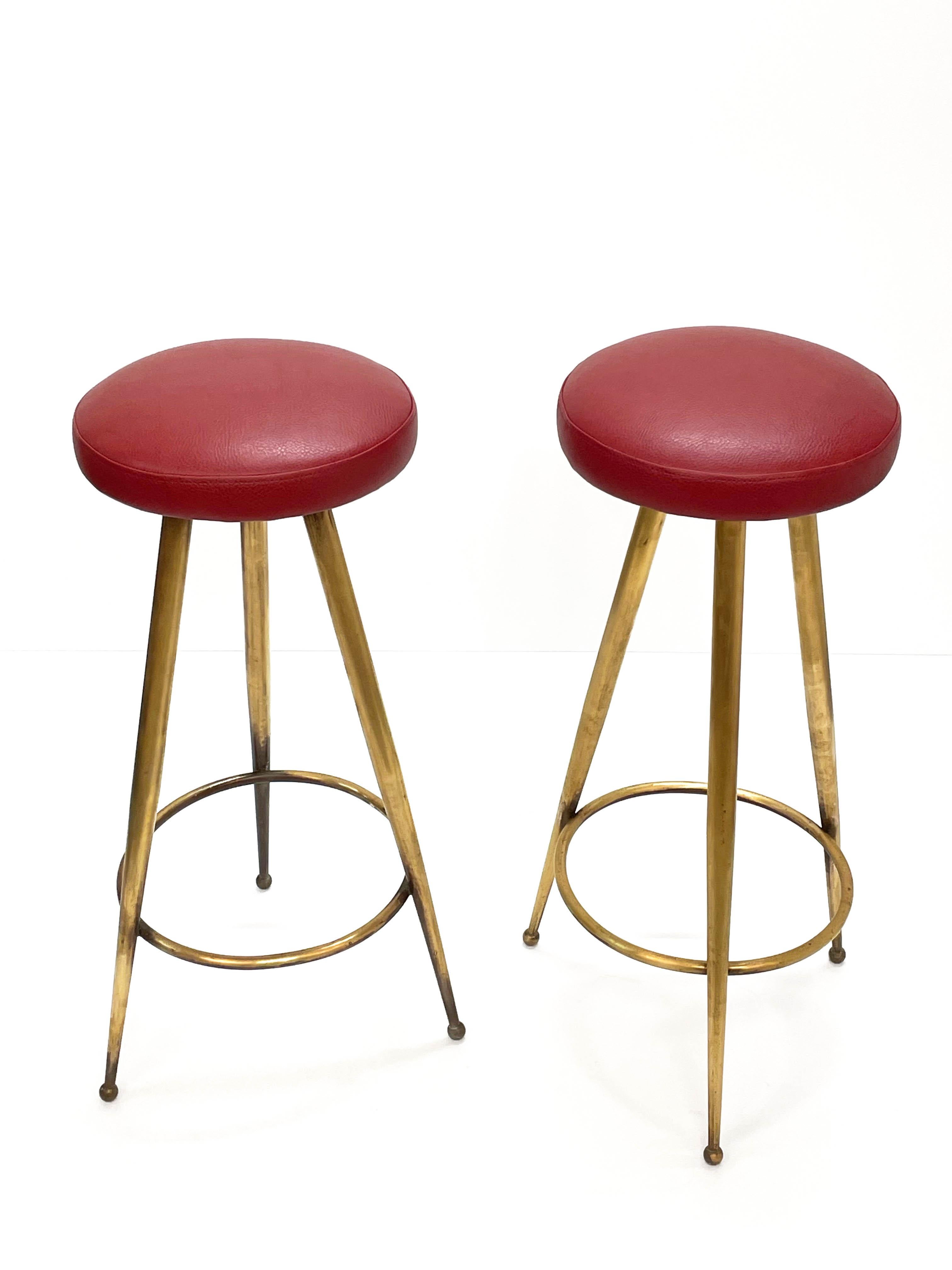 Magnificent pair of Mid-Century Modern bar stool in red vinyl and brass structure. This wonderful set was designed in Italy during the 1950s.

These pair of bar stools were constructed with three solid brass tapered legs on brass ball feet. The