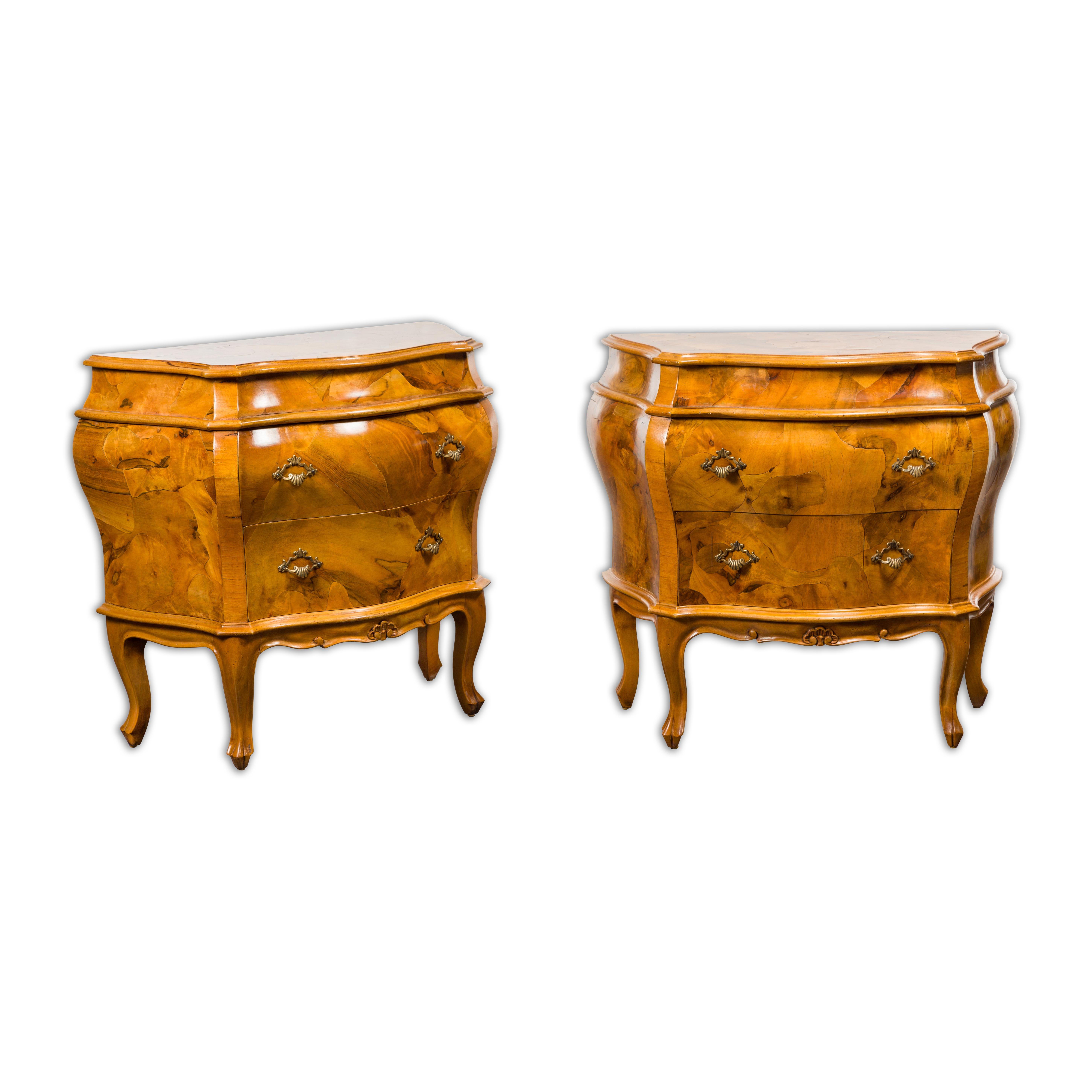 A pair of Midcentury Rococo style walnut bombé bedside chests with two drawers and cabriole legs. Immerse yourself in the elegance of bygone eras with this pair of mid-century Rococo-style bedside chests, an exquisite homage to the lavish French