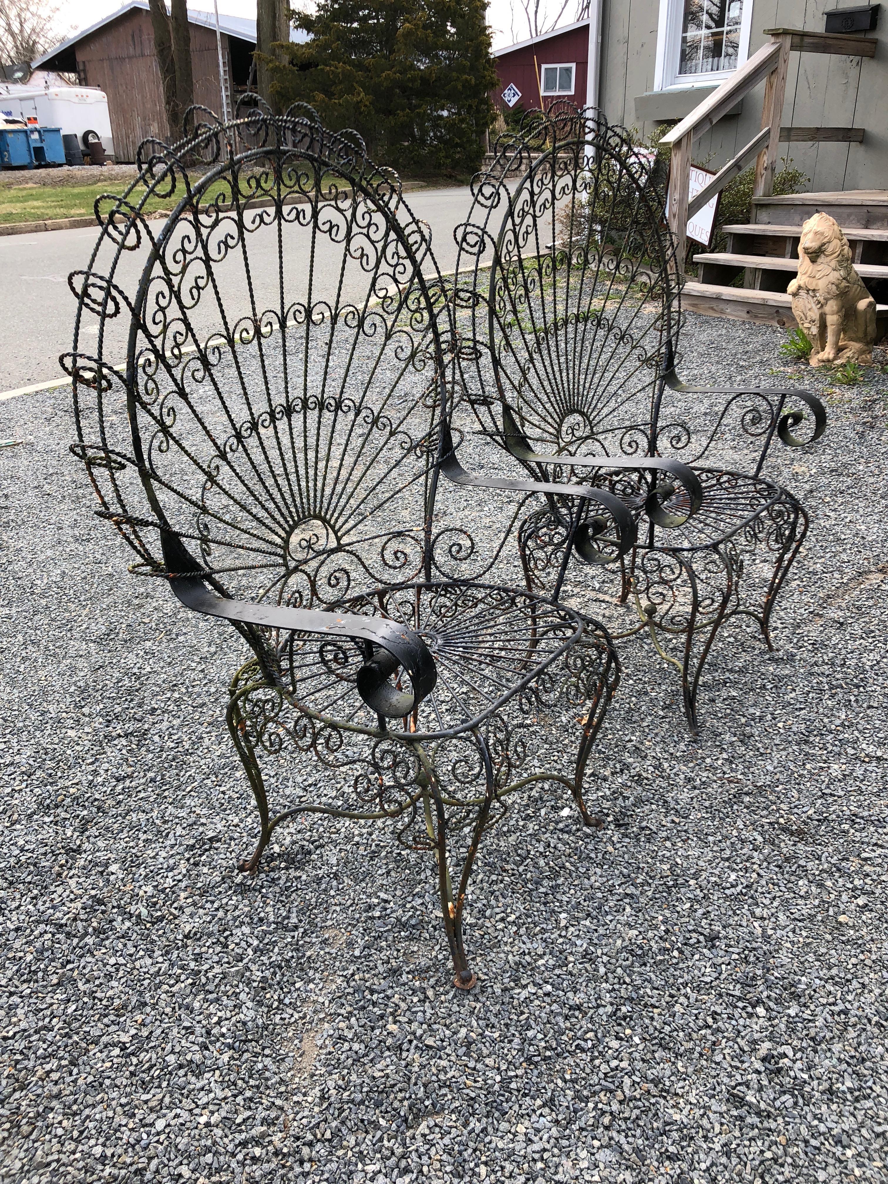 Whimsical pair of Salterini ornate wrought iron twisted wire fan back Peacock patio chairs. 
 This pair is in vintage condition with no cracks or breaks to the frames but with chippy paint and some rust. Arm height 24.