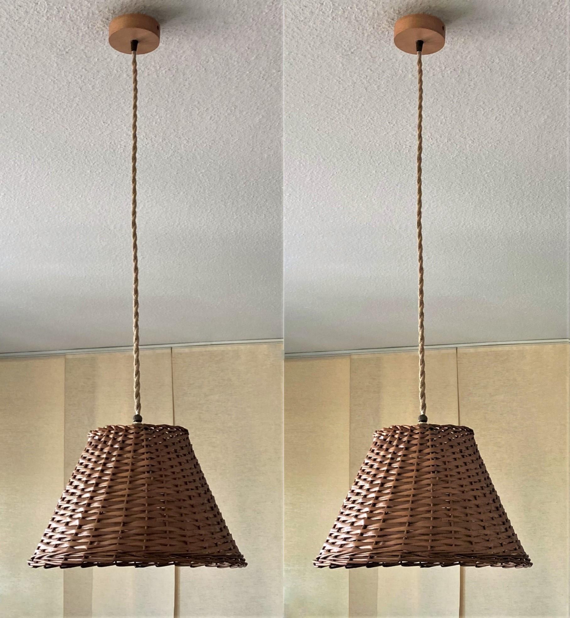 Pair of midcentury rattan pendants, Denmark, 1960s. These beautiful suspension lamps are handcrafted in rattan, lamp shade design with wood canopy. Each pendant with single brass bulb holder for a large sized E27 crew bulb, provinding a warm and