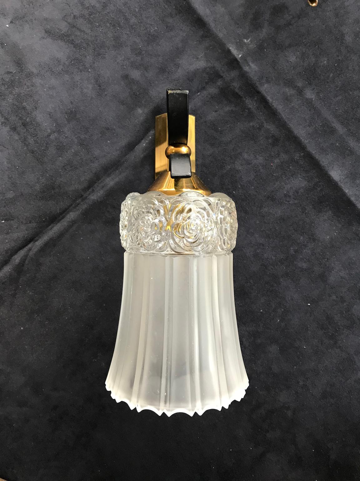 French pair of wall lamp sconces in gilt brass and black wrought iron with beautiful thick glass frosted lampshades with elegant flowers ornaments on the top part. In an excellent condition.
A very chic classy contrast of black, gold and white