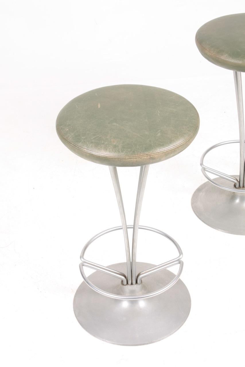 Pair of stools in metal with patinated leather seats. Designed by Piet Hein for Fritz Hansen. Made in Denmark, great original condition.