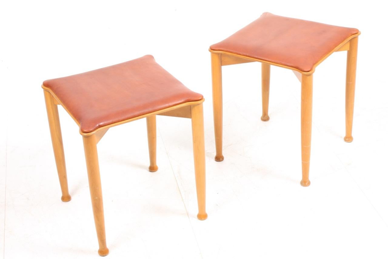 Pair of stools in beech and seat in patinated leather. Designed by Hvidt & Mølgaard in the 1950s.