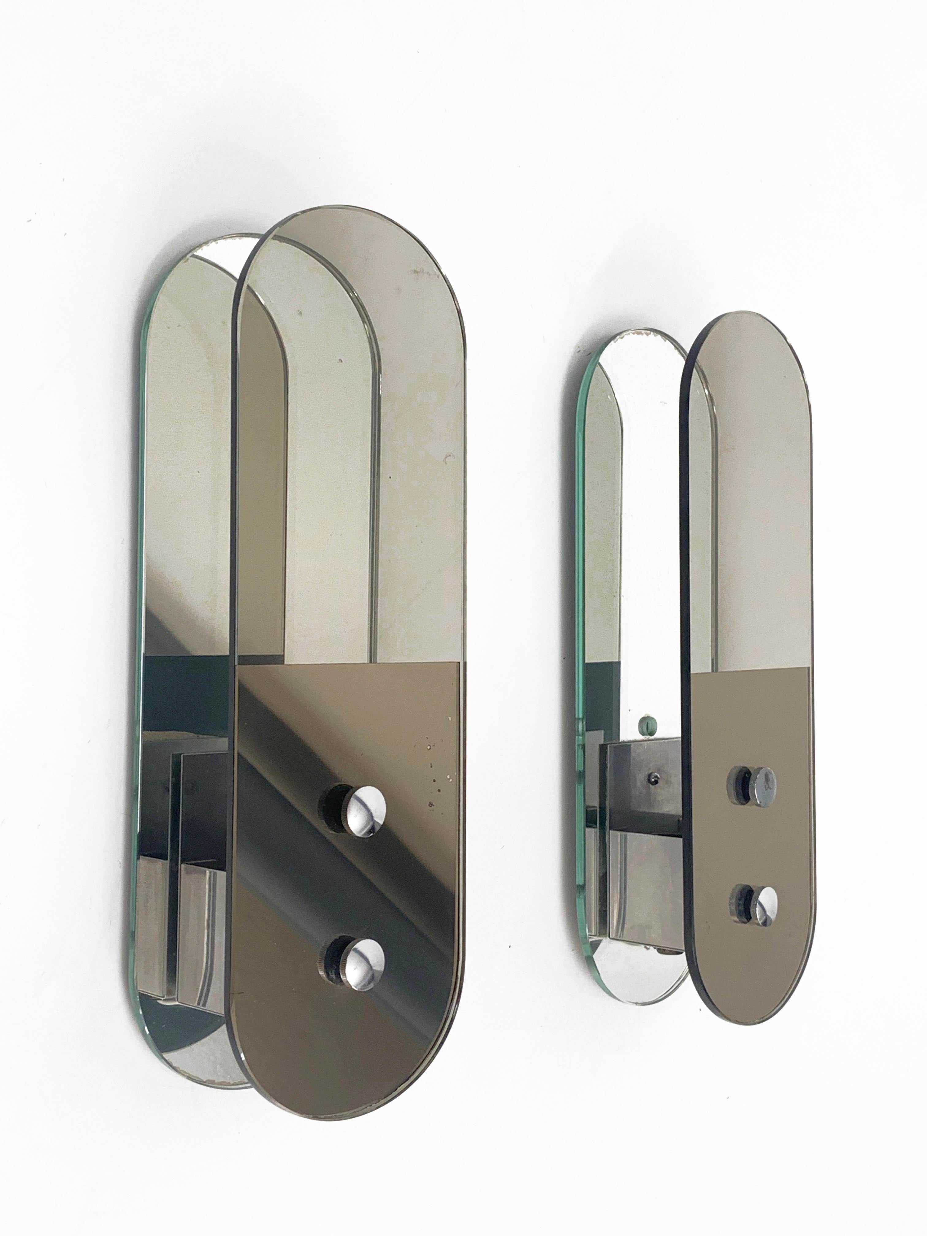 Beautiful and rare pair of midcentury glass and chromed metal mirror sconces. This amazing set produced by Veca in Italy during the 1960s.

These pieces are wonderful thanks to the bevelled glass panels in smoked brown oval shape, partially