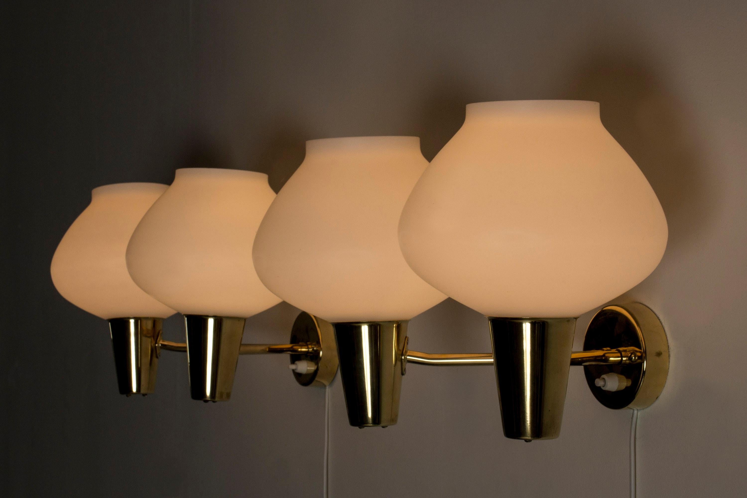 Zwei elegante schwedische Wandleuchten aus der Mitte des Jahrhunderts, aus Messing mit doppelten Opalglasschirmen. Klare, bauchige Formen, die in der Dunkelheit schön leuchten.