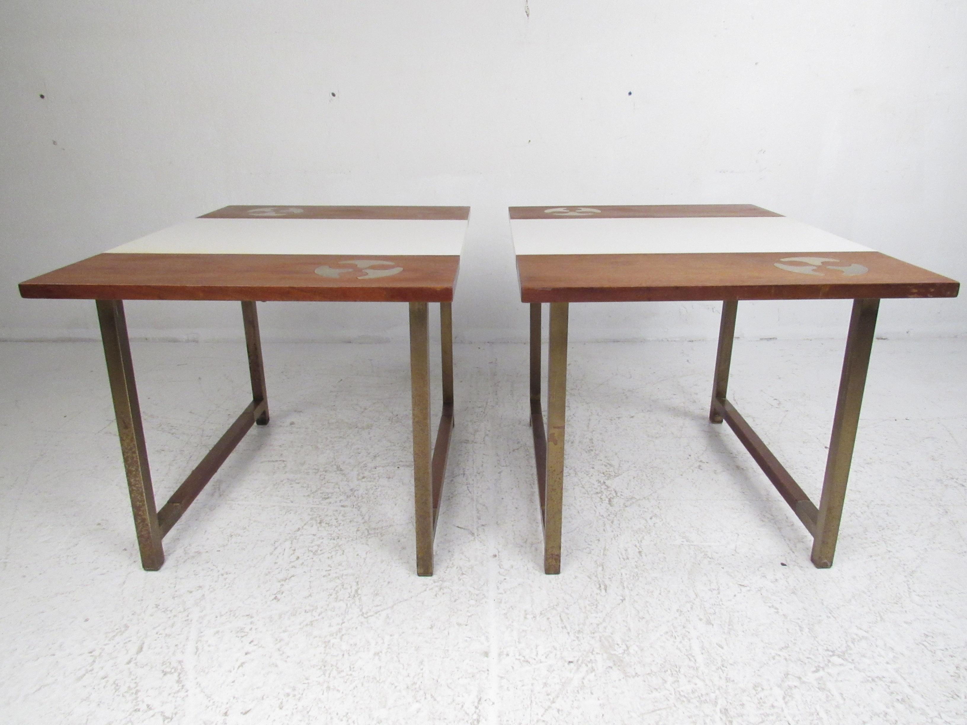 This stylish two-tone pair of vintage modern end tables feature a brass sled leg base. A unique piece that boasts a white formica and walnut top with inlaid brass designs. The brass base has walnut stretchers connecting each side adding to the