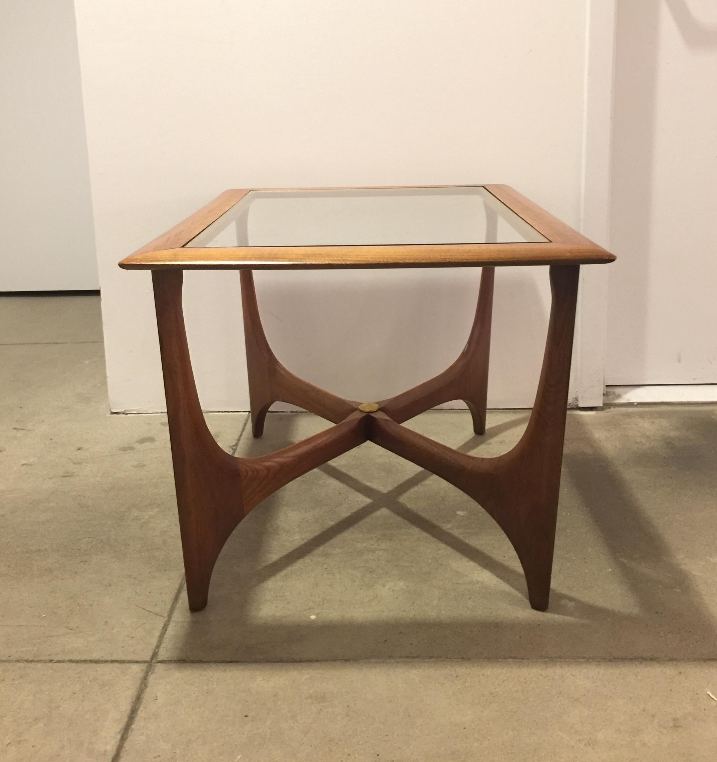 A pair of rectangle-top midcentury walnut tables with crossed stretchers and smoked glass tops, accented by a brass medallion on stretchers. Made in USA, circa 1960.

Dimensions: 19.75 inches H x 30 inches L x 22.75 inches D. 

 