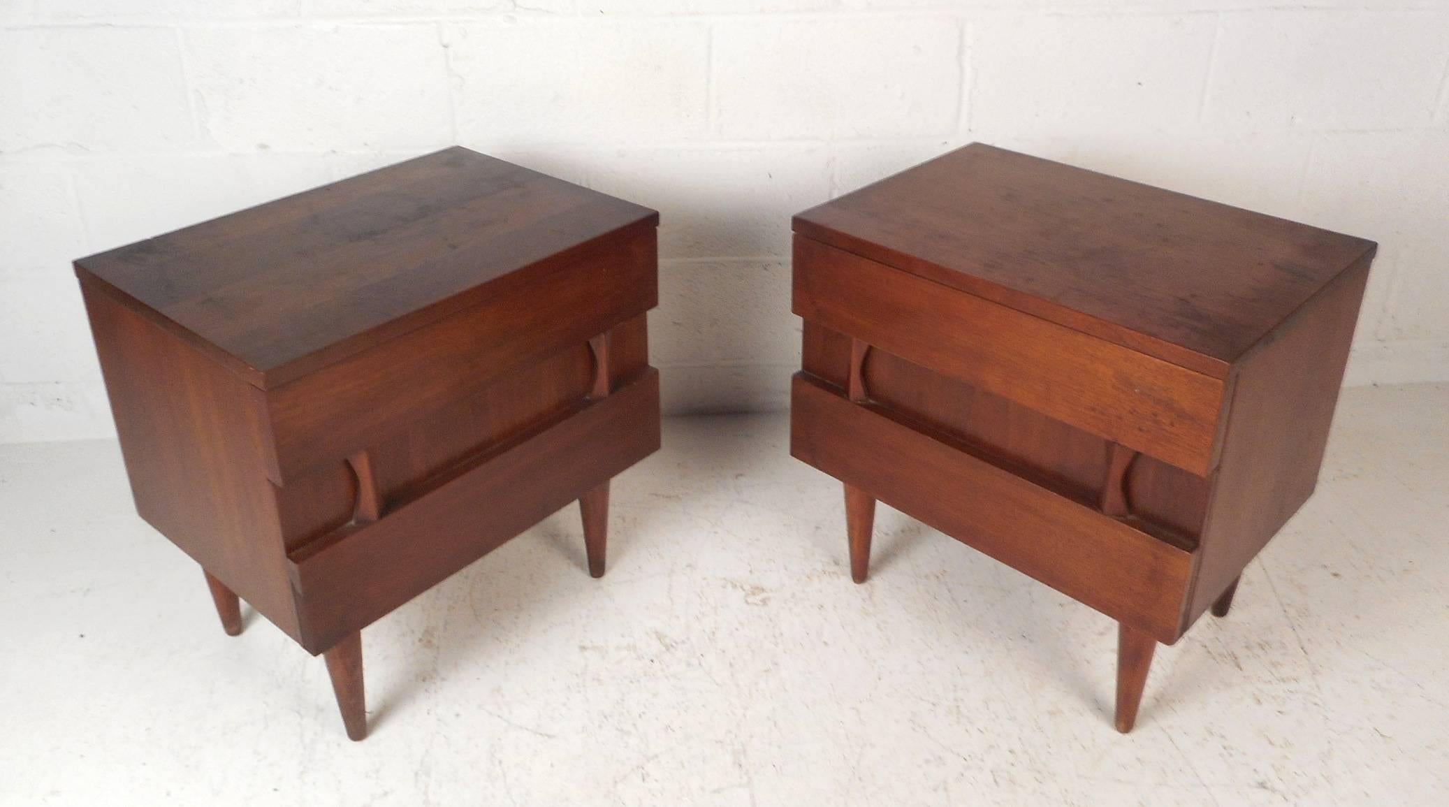 This beautiful Mid-Century Modern pair of nightstands offer plenty of room for storage within there two hefty drawers with sculpted fronts. Sturdy construction by American of Martinsville with a dark vintage walnut finish and tapered legs. Straight