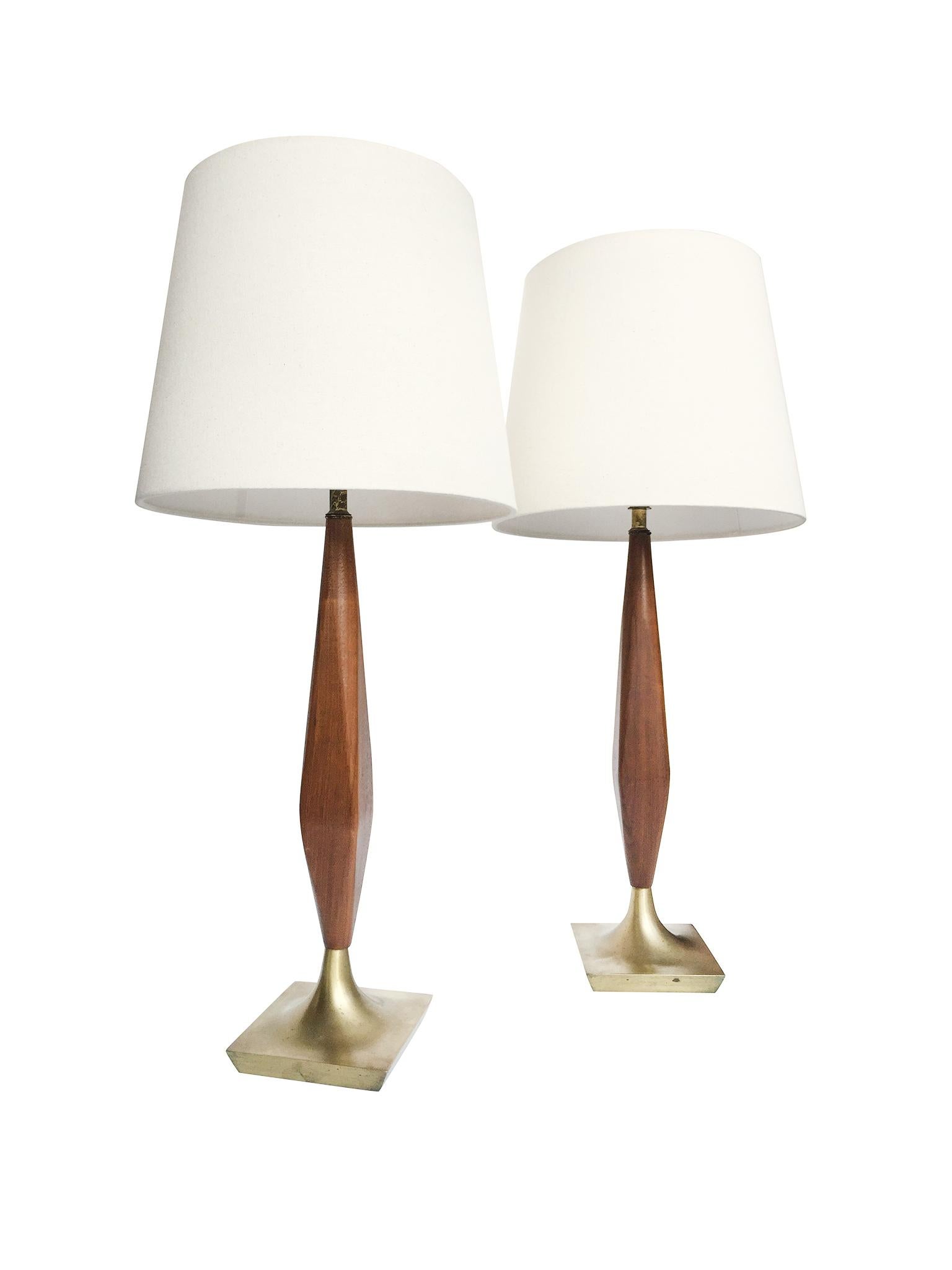 This handsome pair of midcentury lamps is comprised of a walnut stem and a brass base. The hand-crafted woodwork on the walnut is beautiful, with the stem's edges rounded into a spindle form. The brass bases square in shape and bevelled. These lamps
