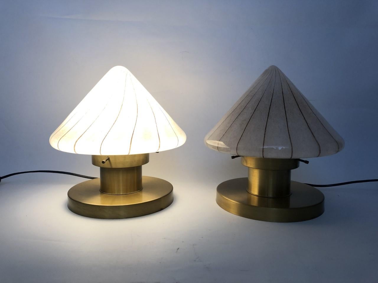 Charming, refined and lovely set of two Italian Murano table lamps. 
These table lamps were made during the 1970s in Italy.
Each table lamp is composed gold brass structure and a piece of Murano Glass for the top.
Each table lamp is equipped with