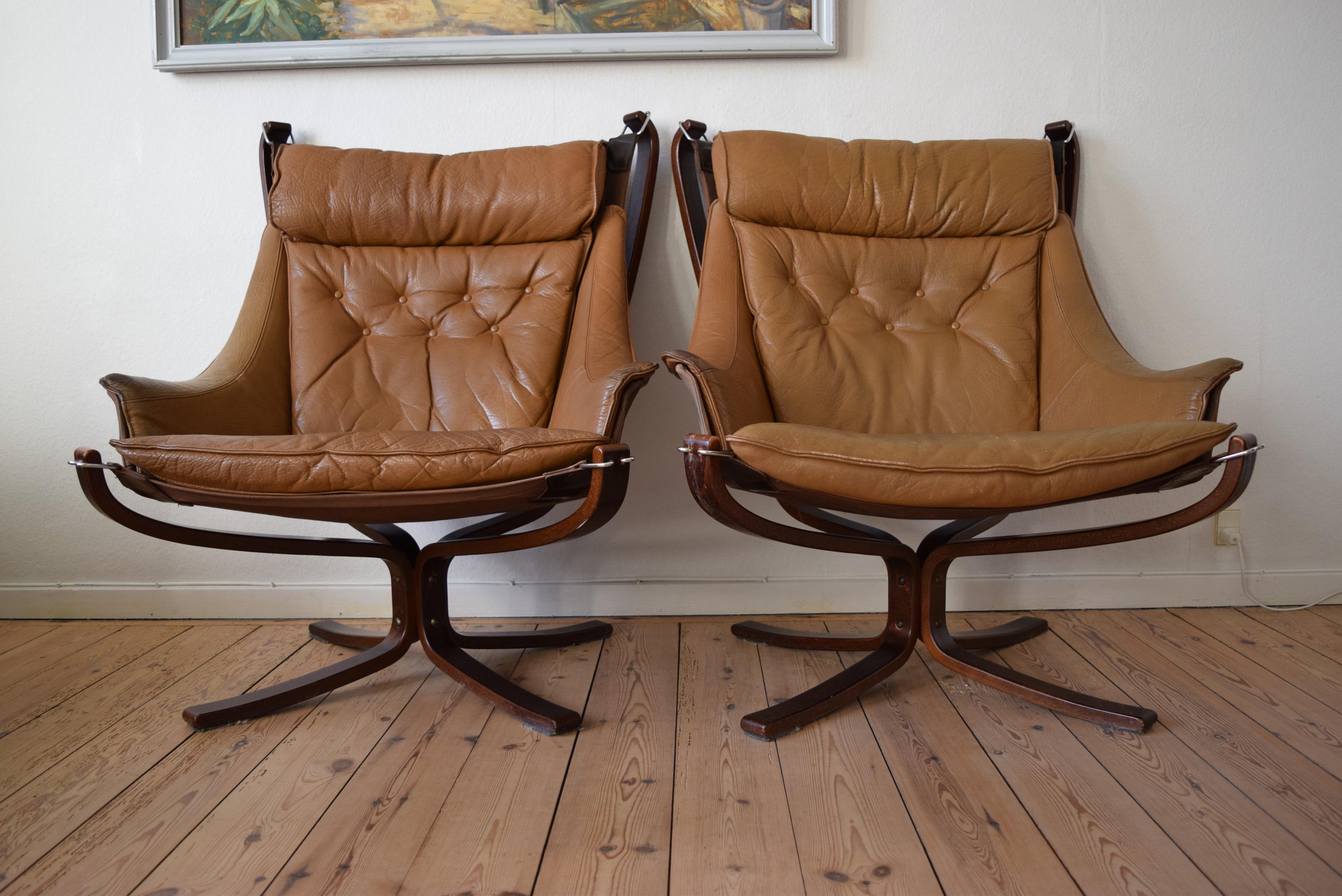 This pair of winged ‘Falcon' lounge chairs were designed by Sigurd Resell during the 1970s and were produced by Vatne Møbler, Norway. In a very good vintage condition, the pieces are made with light tan leather cushions on a bentwood frame, and hang