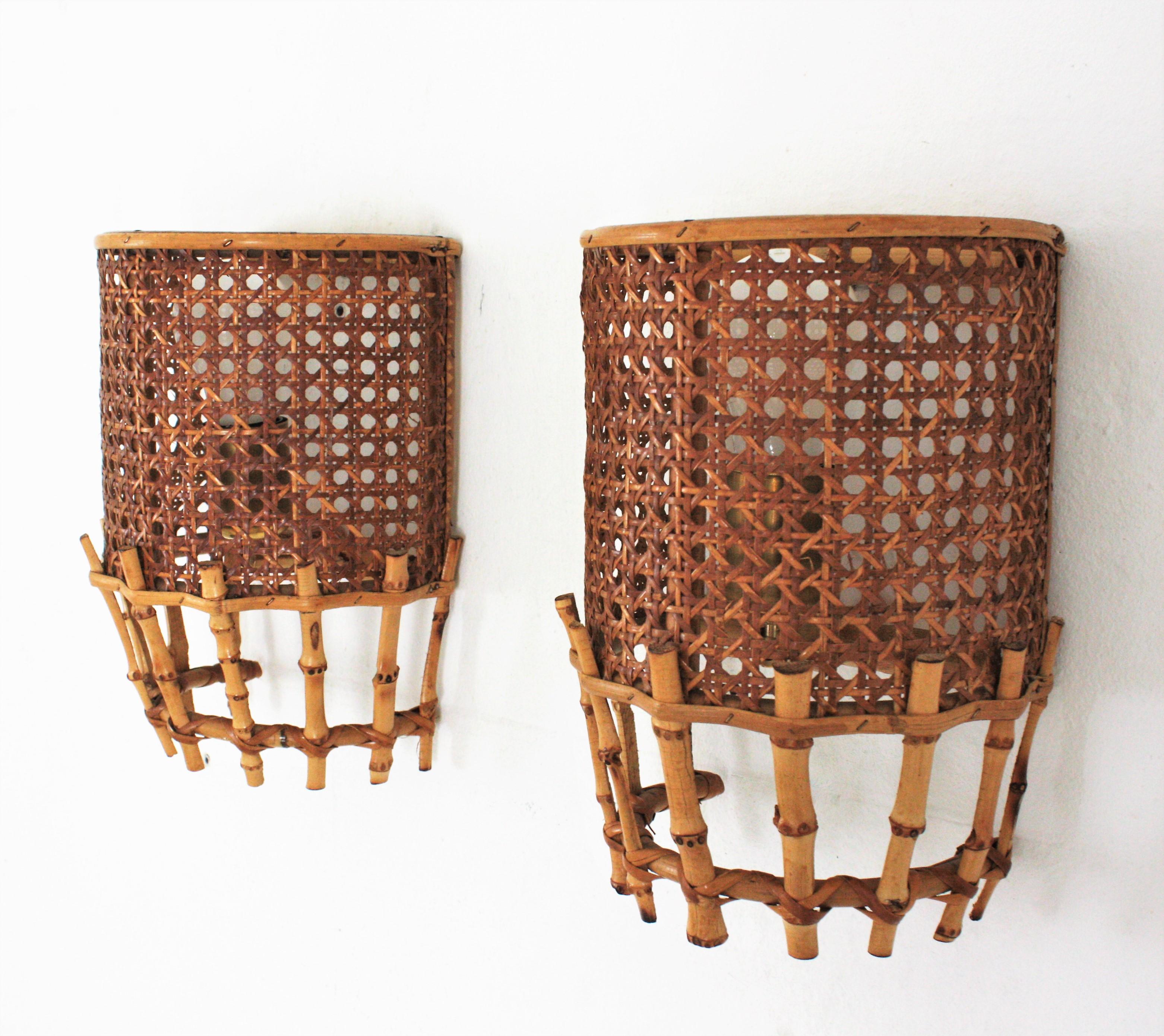 Pair of half cylinder wall lights with wicker and rattan woven shades and bamboo accents, France, 1960s.
These light fixtures are made with wicker basket weave panel on a rattan semi cylindrical structure accented by bamboo canes at the bottom