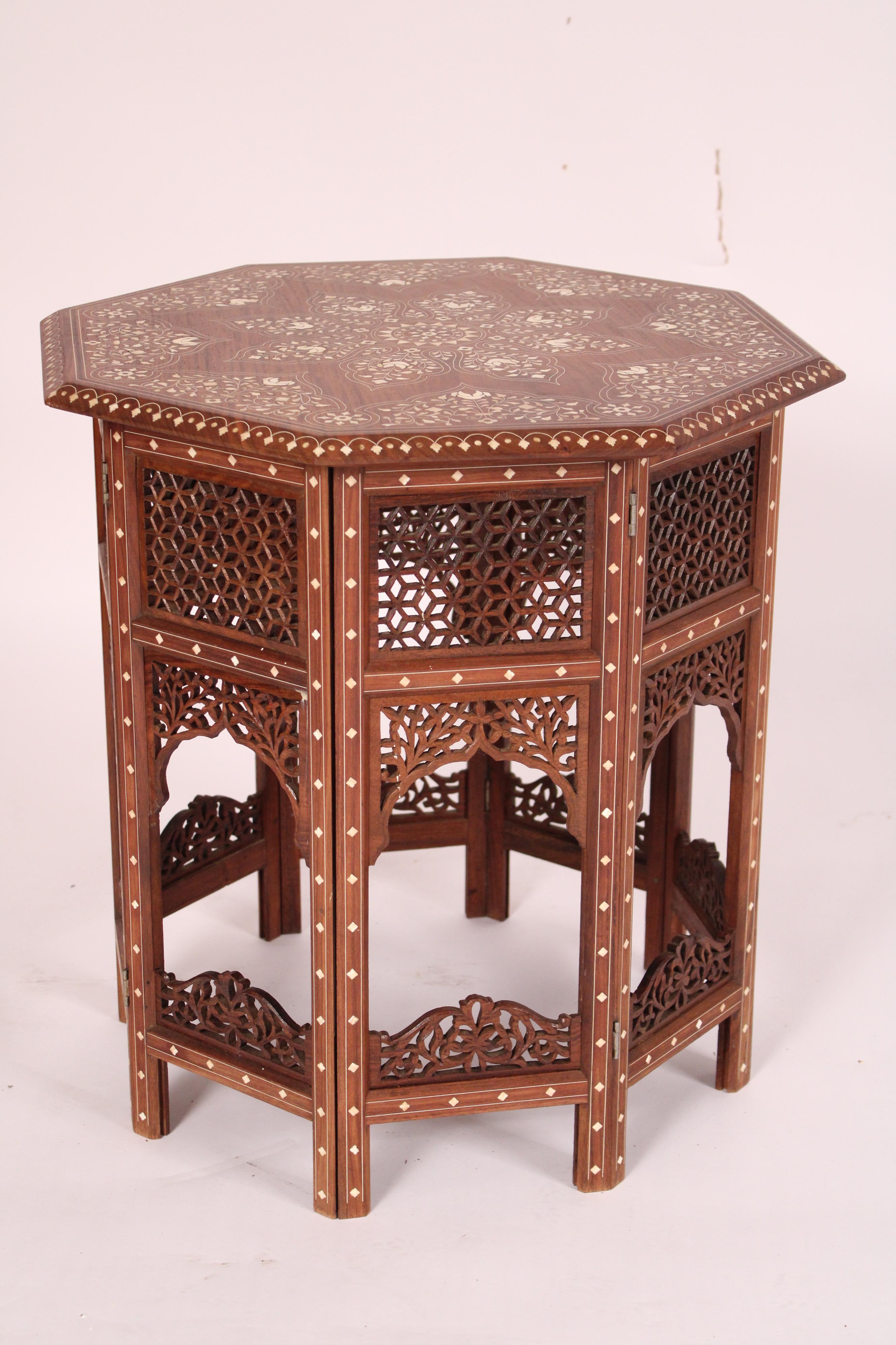 Pair of Middle Eastern bone inlaid octagonal shaped side tables, circa 1980's. With removeable octagonal shaped tops with extensive bone inlay, the bases with reticulated and bone inlaid sides. The bases are collapsable / foldable for transporting