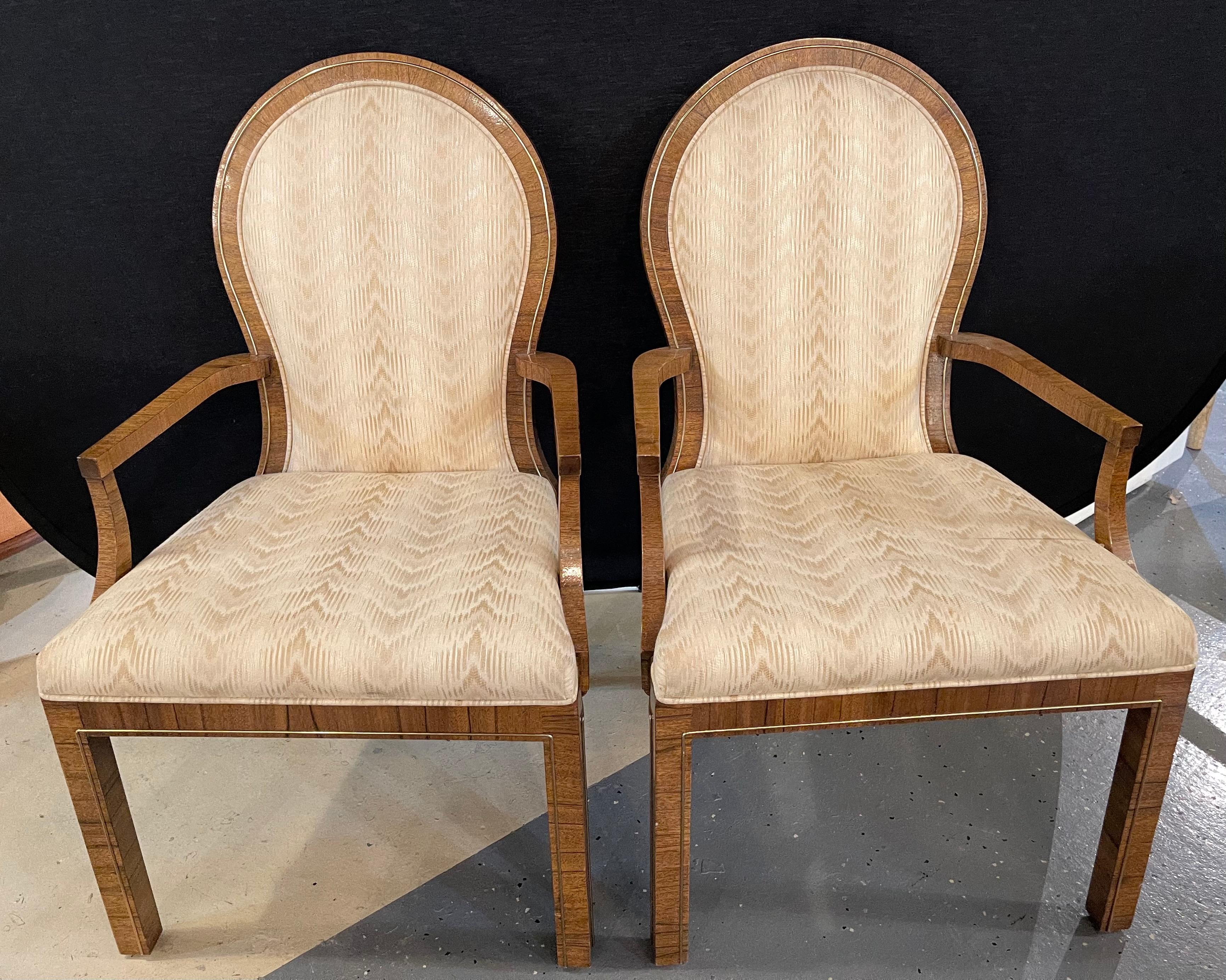 Pair of Mid-Century Modern arm chairs by Milo Baughman. Each with burlwood frames having brass framing. Made by Mastercraft.