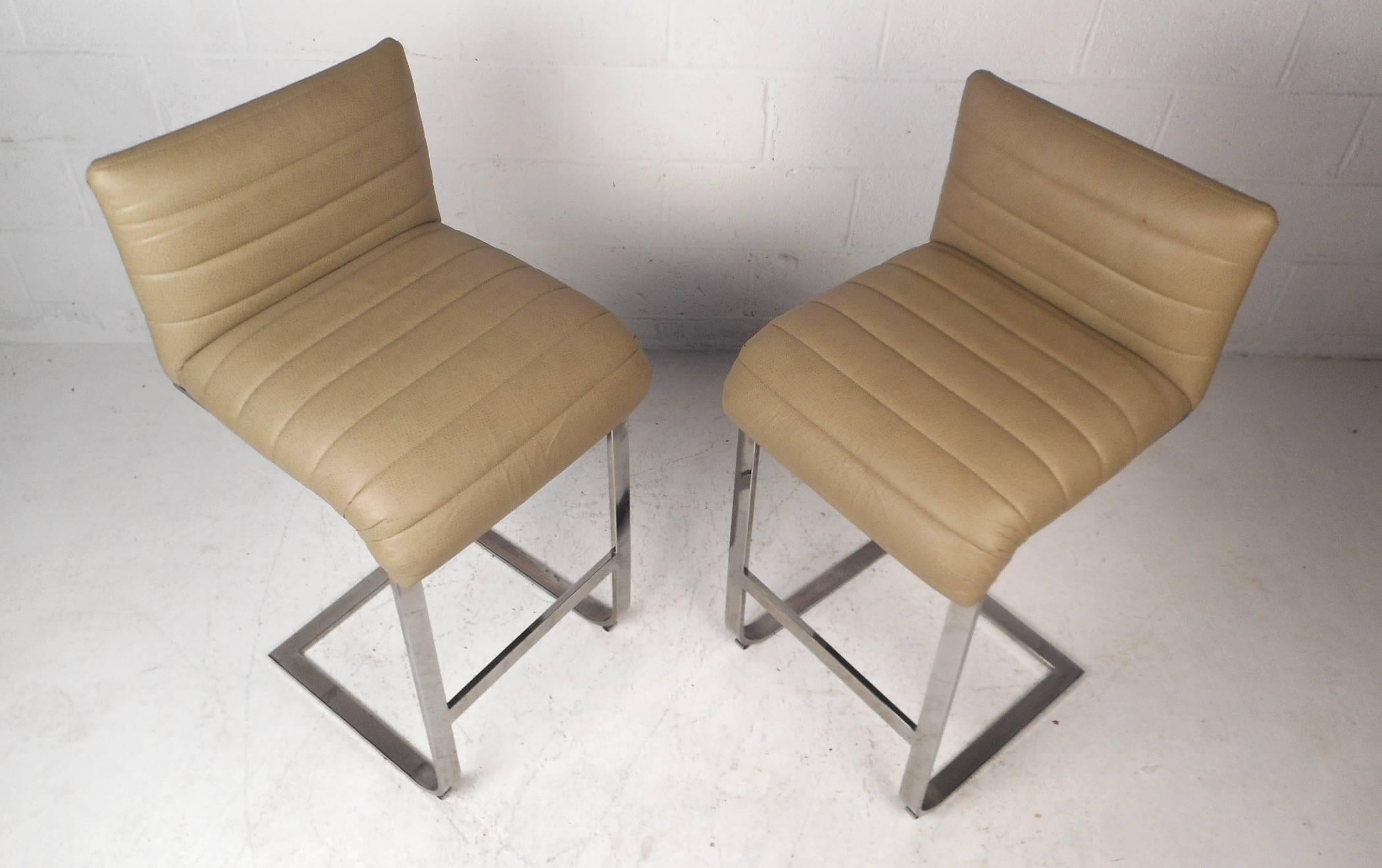 This beautiful Mid-Century Modern pair of bar stools feature heavy flat bar chrome frames. Slipper design with a thick padded seat and backrest ensures maximum comfort without sacrificing style. Lovely beige colored upholstery adds to the allure.