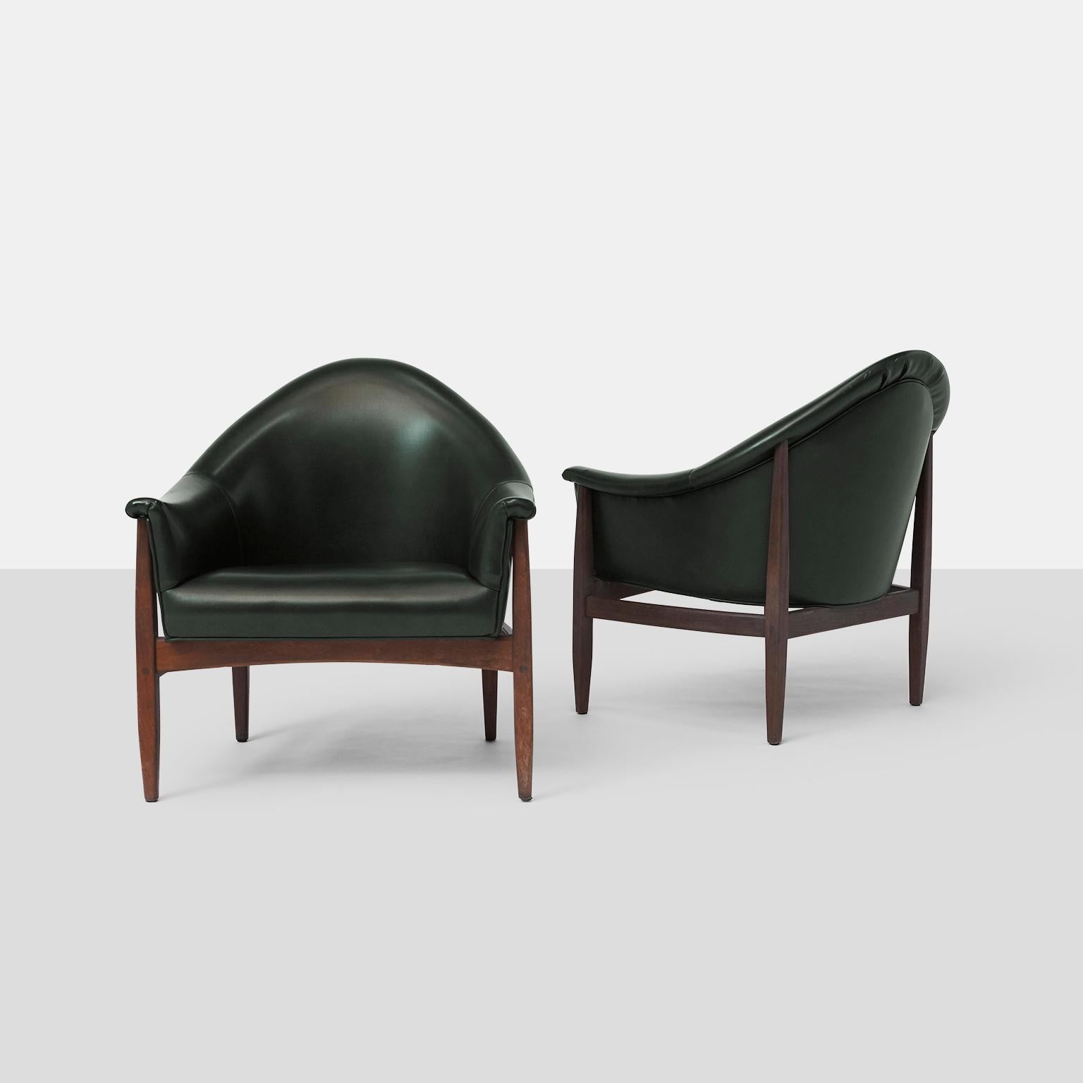 A pair of round back club chairs by Milo Baughman for Thayer Coggin. A rare, early style that marked the beginning of their long collaboration. 
Walnut frames support low scoop seating and covered in a dark green vinyl.