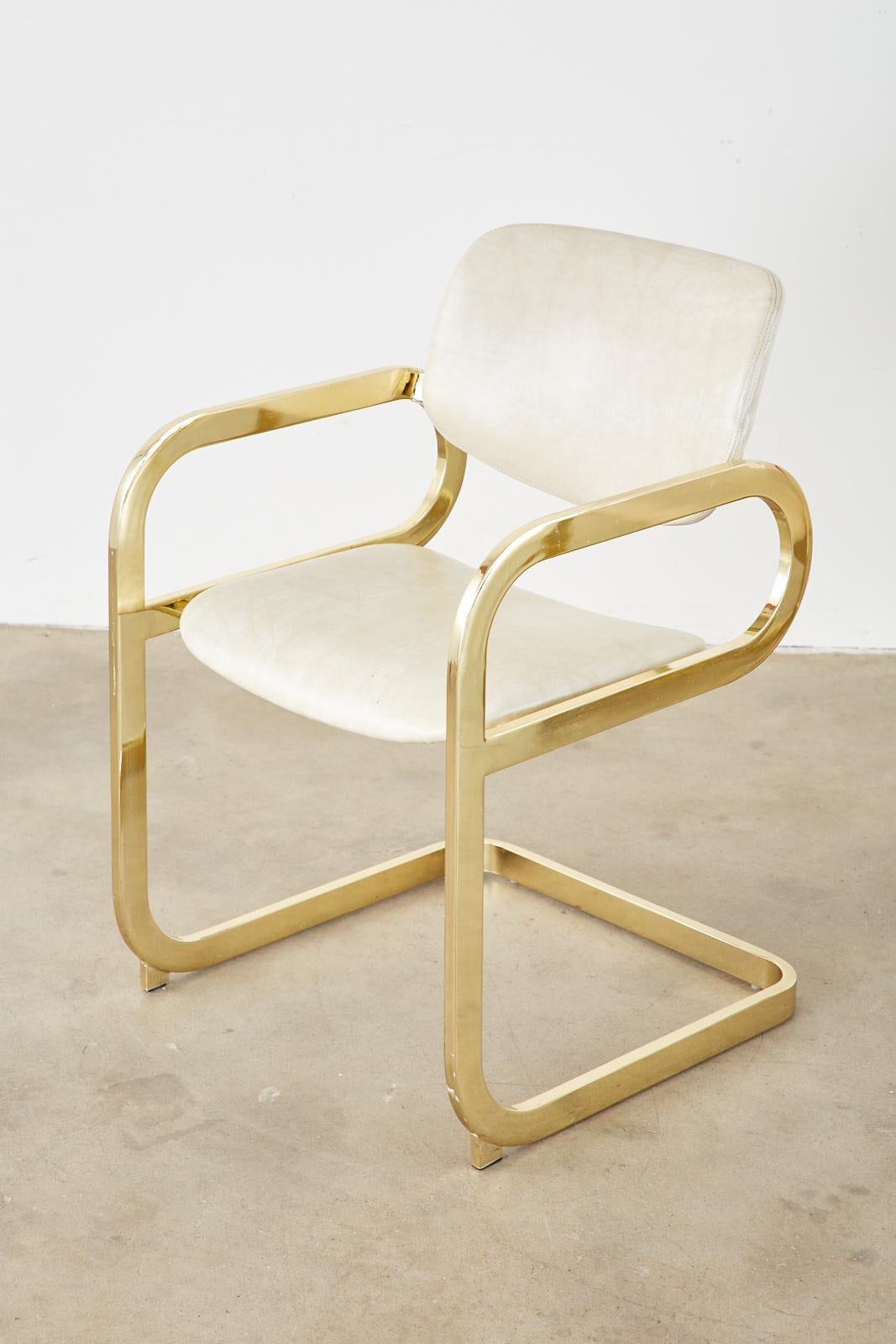Chic, mid-century modern associated pair of Hollywood Regency gold cantilever dining chairs or lounge chairs by DIA (the Design Institute of America). Each armchair beautifully plated gold constructed with a flat bar design. Each upholstered with a
