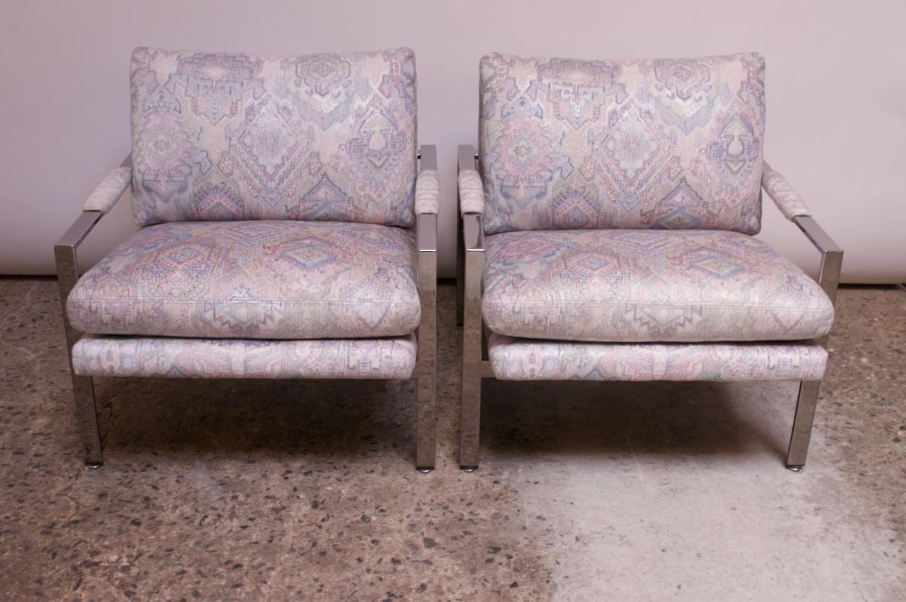 Pair of circa 1970s Milo Baughman for Thayer Coggin chrome arm or lounge chairs. Elegant profile with sharp, slanted lines and a low-slung seat. Fabric was changed around the early 1980s / 1990s and is a heavily patterned purple, pink, peach, green,