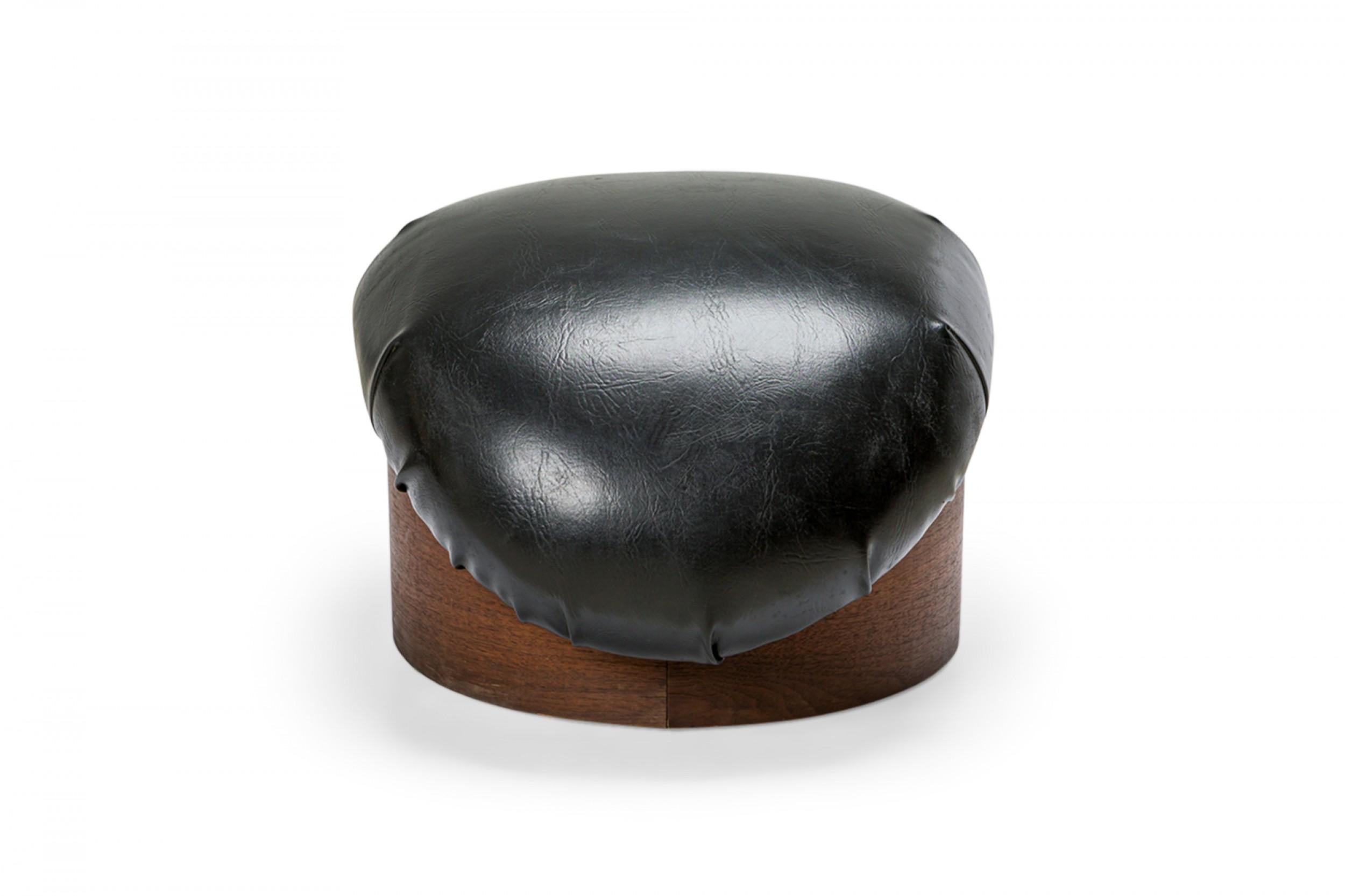 PAIR of American Mid-Century ottomans with curved black leather cushions supported by a circular wooden base. (MILO BAUGHMAN FOR THAYER COGGIN)(PRICED AS PAIR)