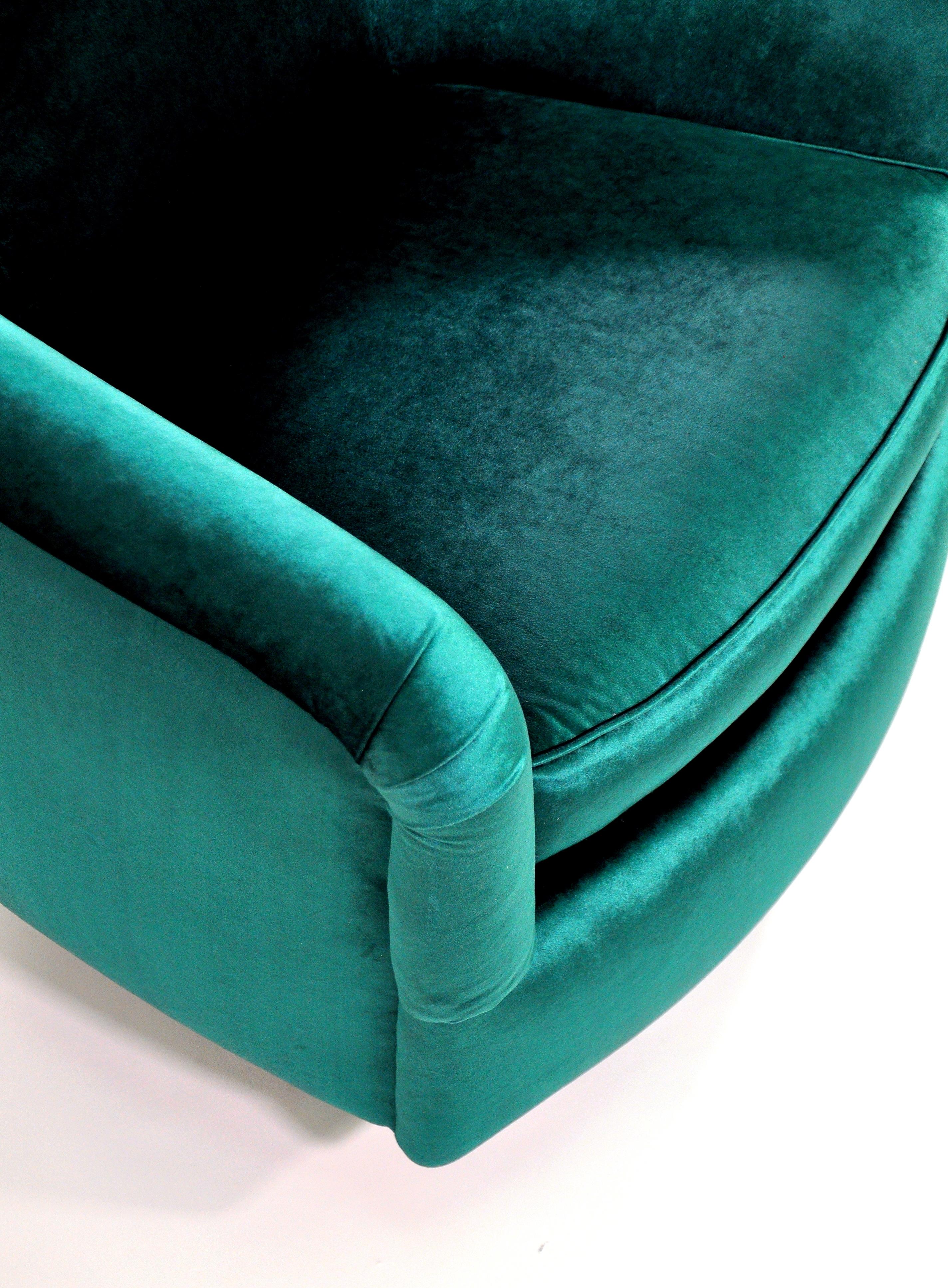 A fabulous pair of Mid-Century Modern barrel back swiveling and rocking club chairs, designed by Milo Baughman for Thayer Coggin, dating from the 1980s. Reupholstered in a luxurious and rich emerald green jewel tone velvet, each armchair features an