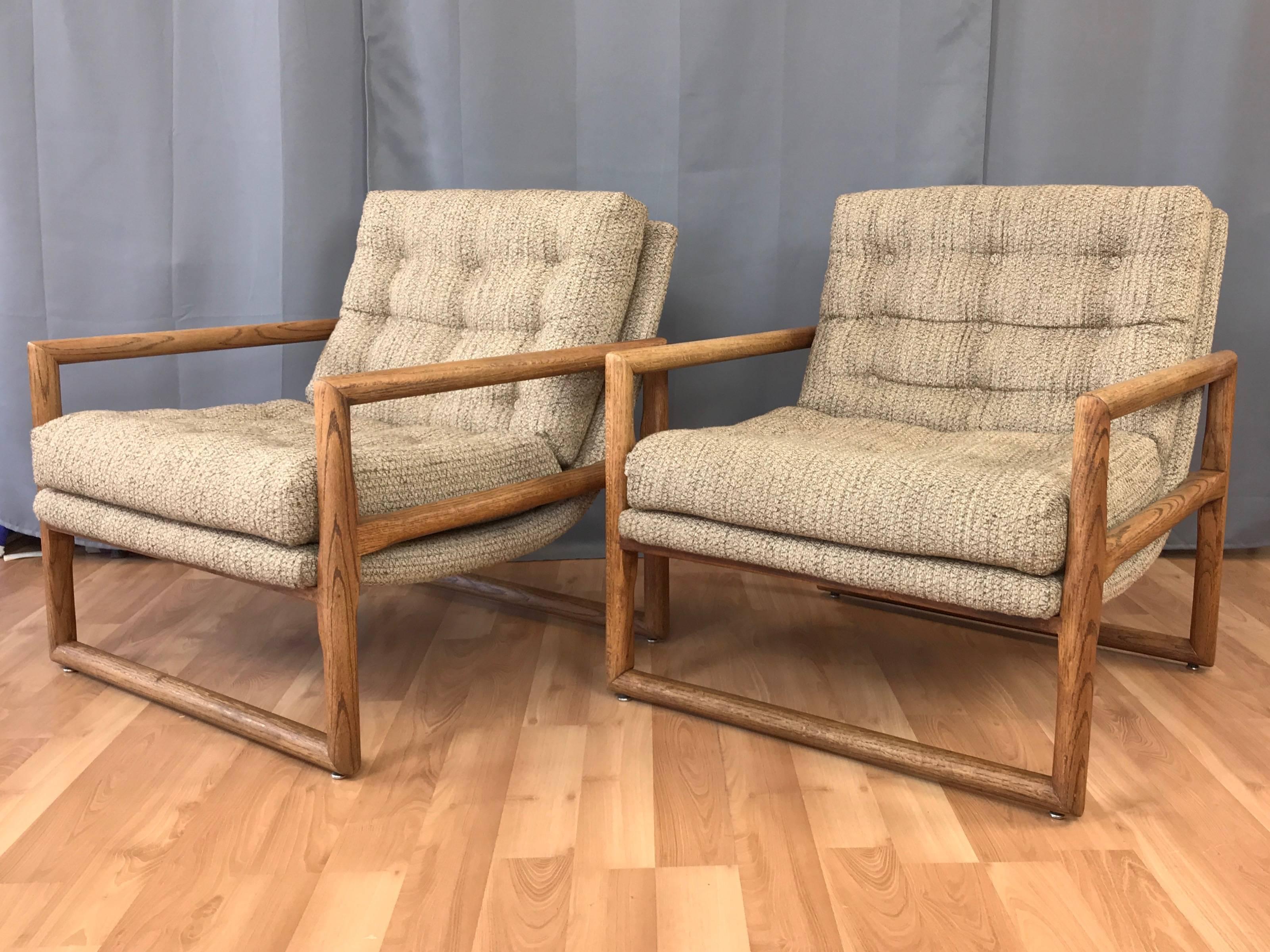 A pair of oversized oak “Scoop” or “Cube” lounge chairs by Milo Baughman for Thayer Coggin.

Substantial solid oak frame’s geometric lines are softened by cylindrical supports and hand-shaped tapered side supports with dado cut joinery. In the