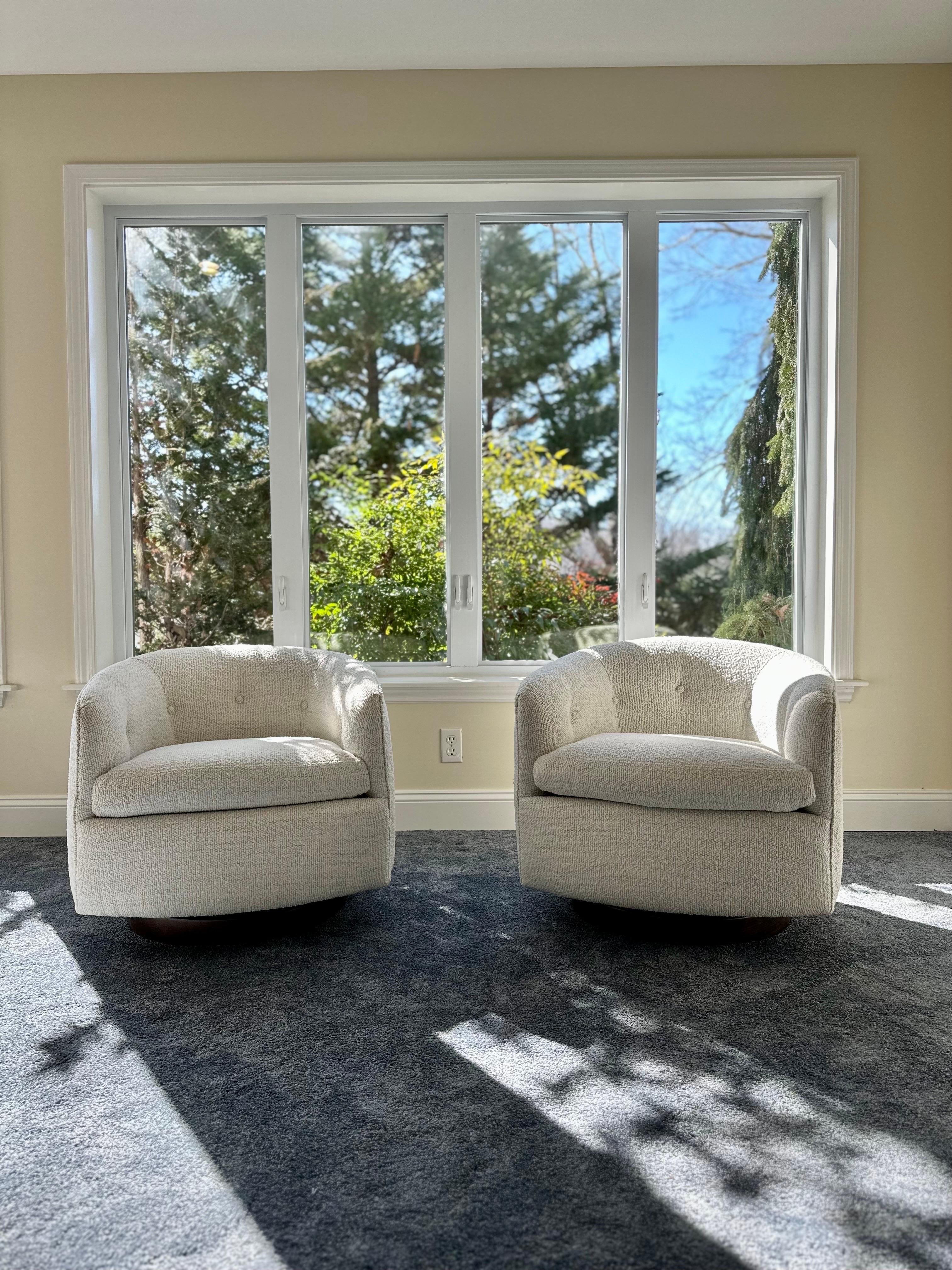 Experience unparalleled style and comfort with this extraordinary pair of swivel and tilt club chairs designed by Milo Baughman for Thayer Coggin. Recently upholstered in a soft and luxurious cream boucle. The walnut bases have undergone