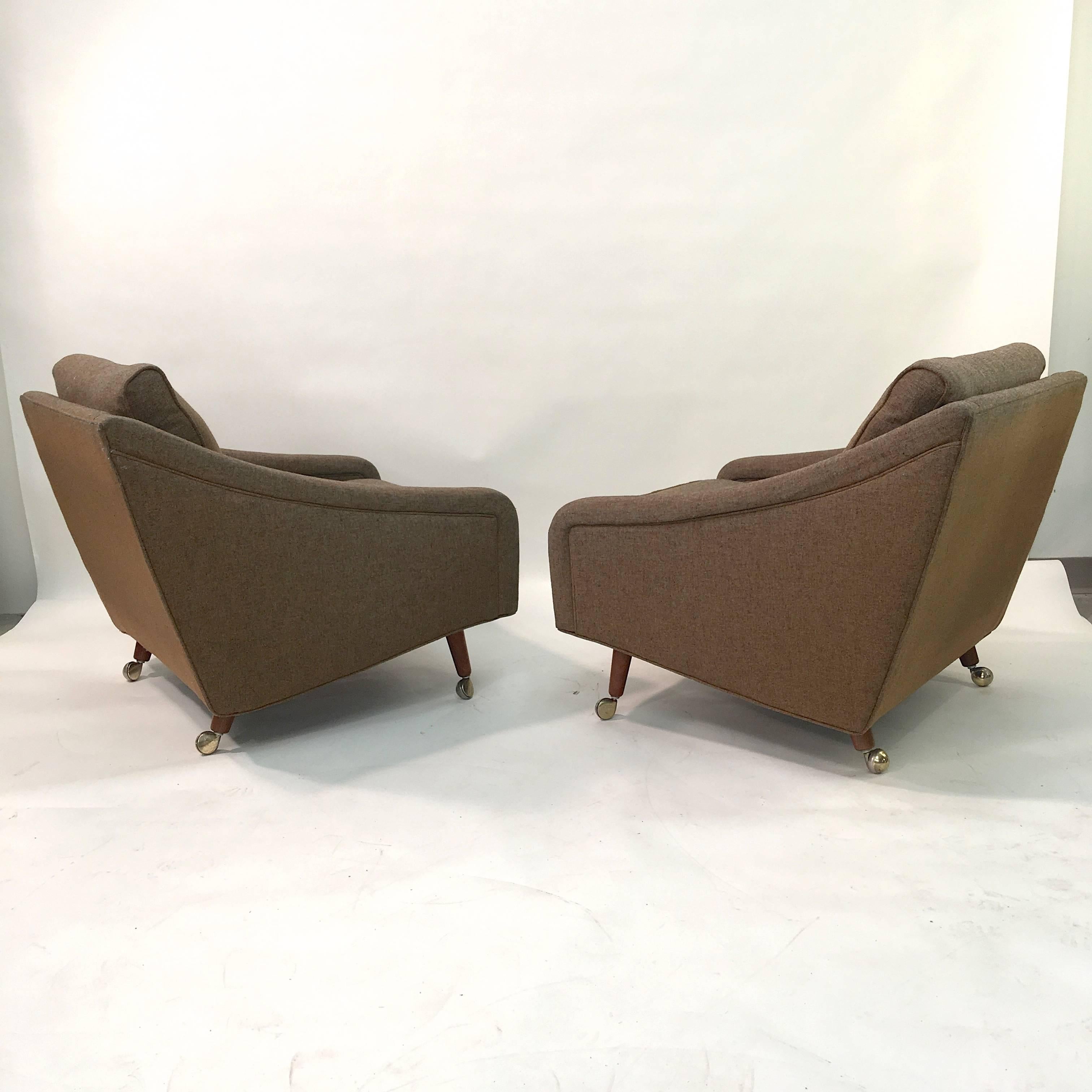 Uncommon pair of 1965 Milo Baughman for Thayer Coggin upholstered lounge chairs with casters on all four feet. Very attractive silhouette. Original loden green wool fabric and original labels present on both chairs.
