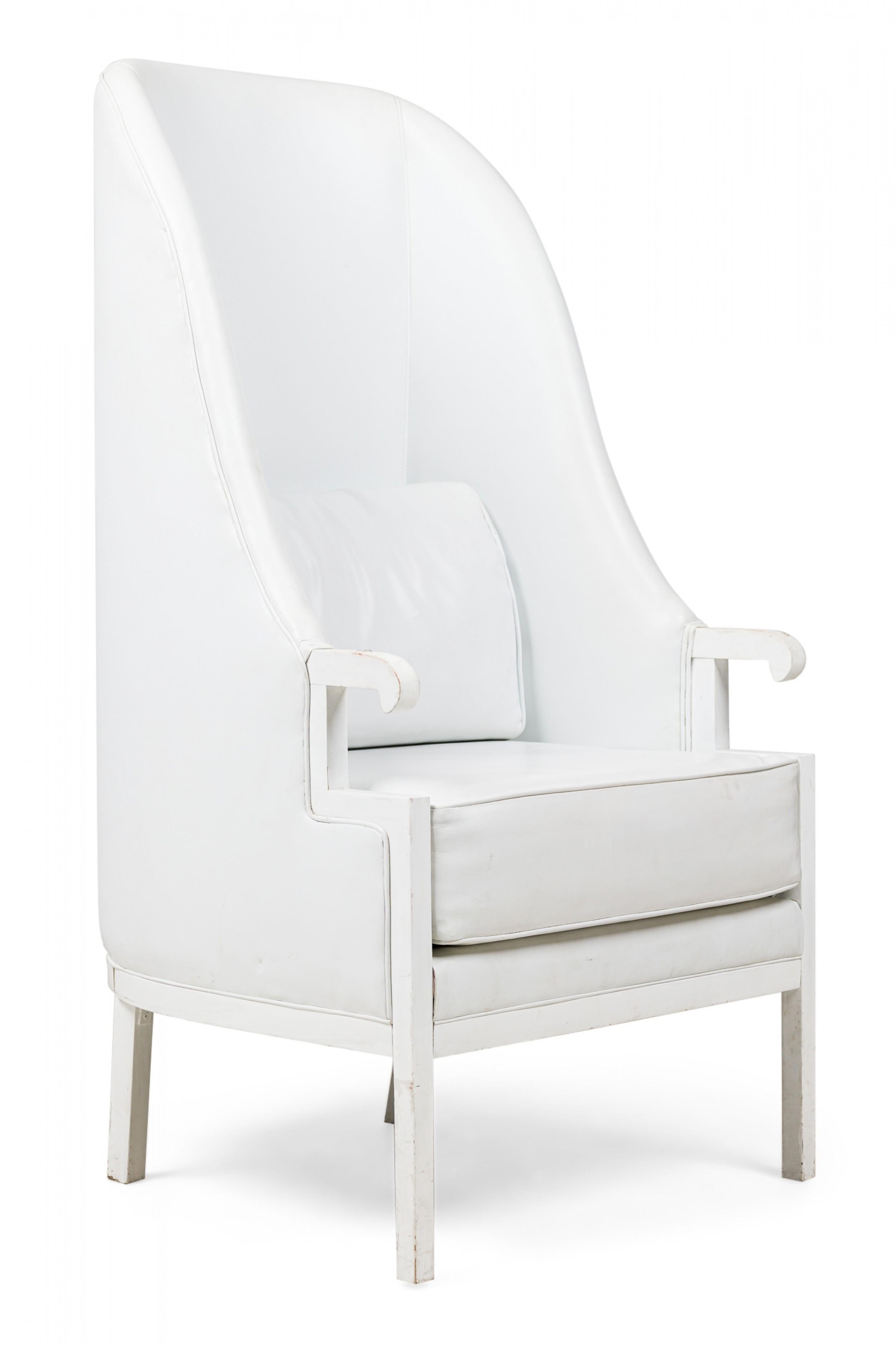 PAIR of Mid-Century Modern armchairs with white painted wooden frames, high backs that wrap around to create two tapered wings, and small curved armrests, the backs, seats, and cushions upholstered in white leather with matching piping, resting on