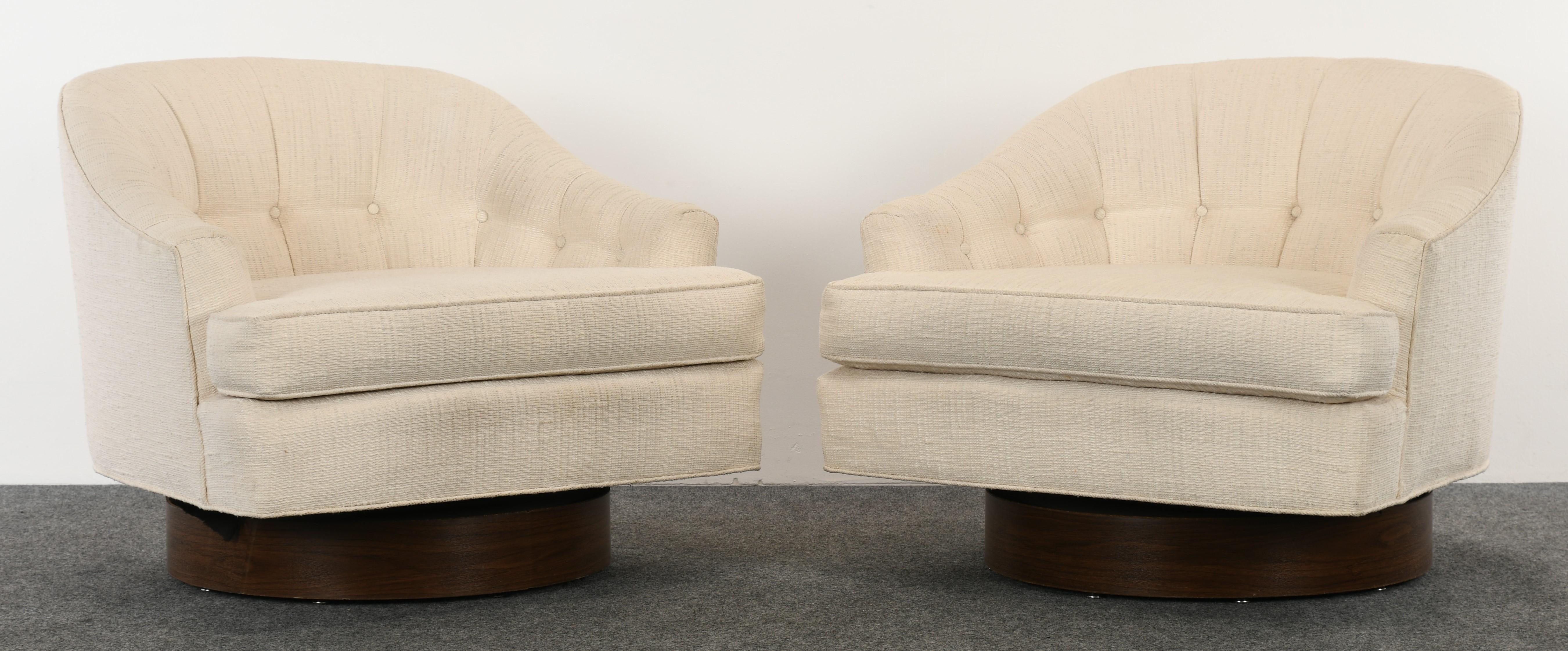 A pair of Milo Baughman style swivel chairs, possibly made by Selig. The chairs have walnut finish bases that appear to be a superb photocopy of veneer, well-done looks exactly like wood. The chairs are structurally sound and in very good condition