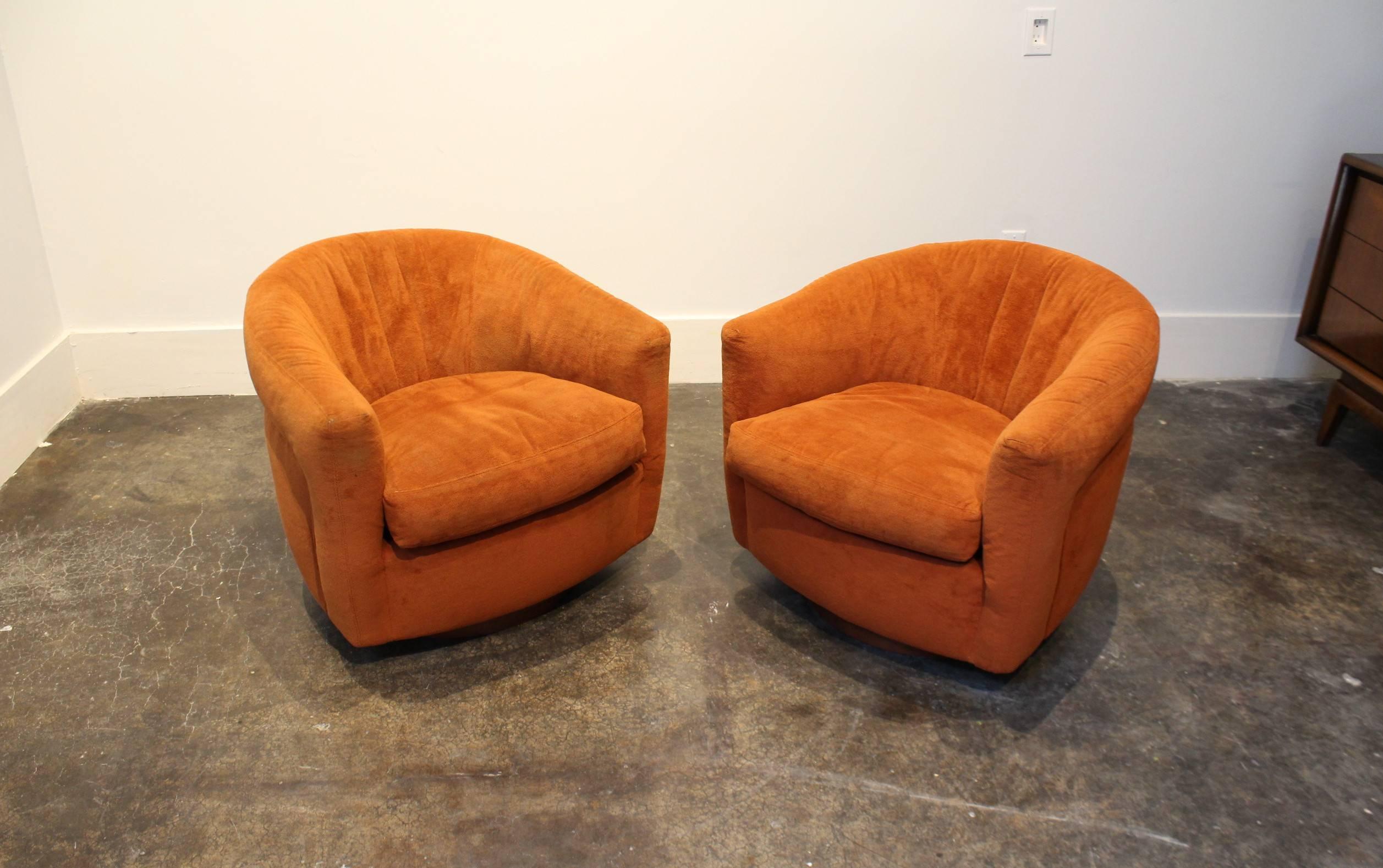 Pair of Milo Baughman for Thayer Coggin swivel and tilt tub chairs from the 1970s with original tags and upholstery. Tapered tub shape upholstered in rust orange fabric on circular walnut wood base.